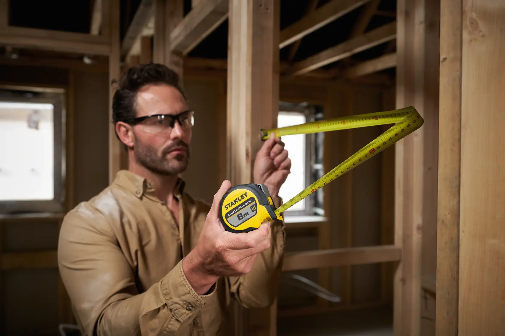 Stanley STHT37232-0 tape measure used for measuring wooden frame, yellow and black casing.