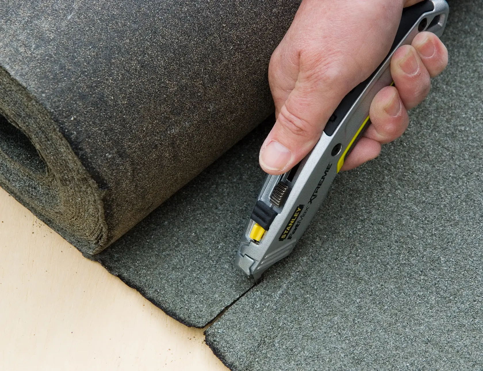STANLEY 0-10-789 utility knife cutting grey roofing material, close-up photo of product in use.