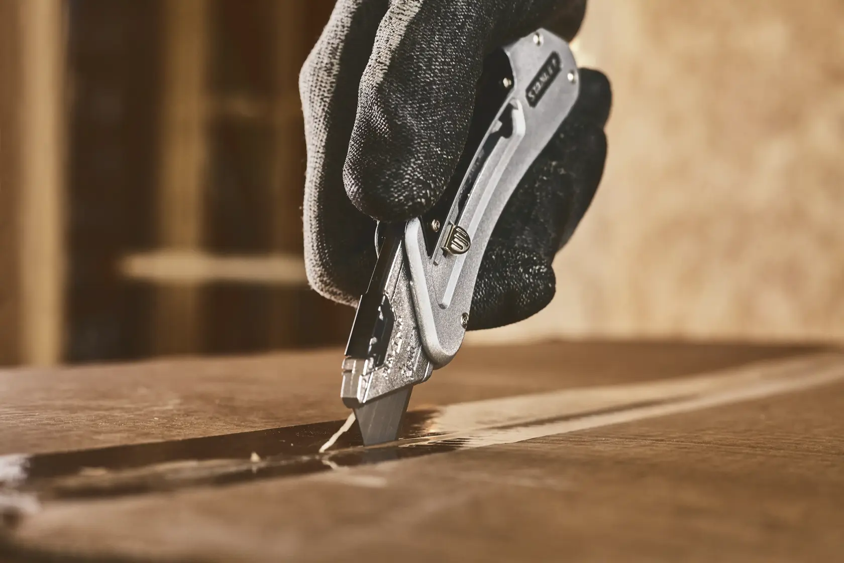 STANLEY 0-10-810 utility knife cutting cardboard, close-up with gloved hand, product photography.