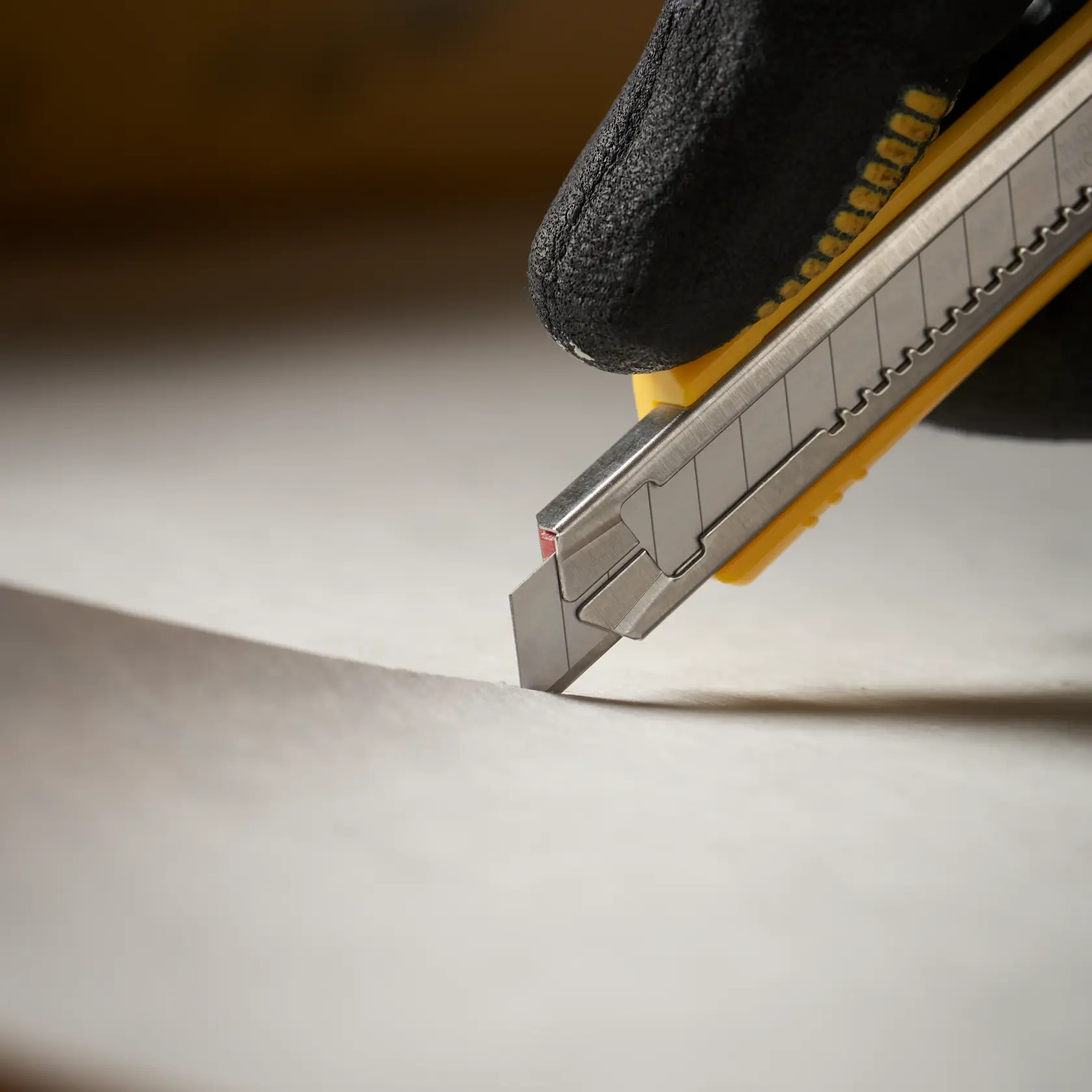 STANLEY 0-11-300 utility knife cutting paper, close-up angle, silver blade with yellow handle