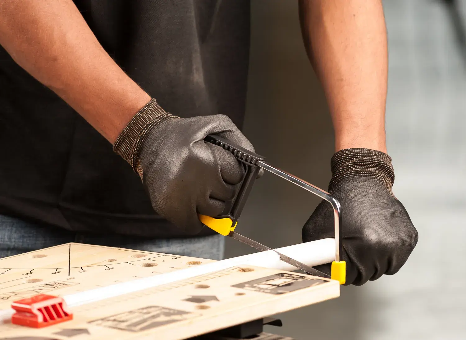 STANLEY 0-15-218 hacksaw being used to cut a plastic pipe on a workbench, close-up view.
