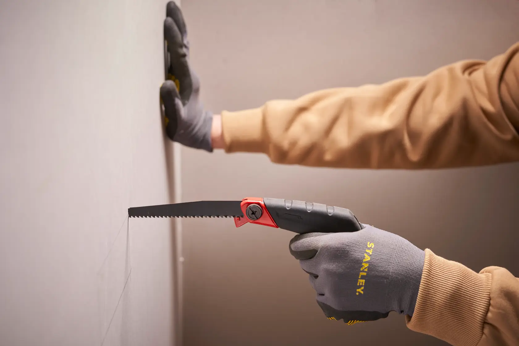 Stanley 0-20-108 folding saw, black and red handle, used to cut drywall, close-up photography.