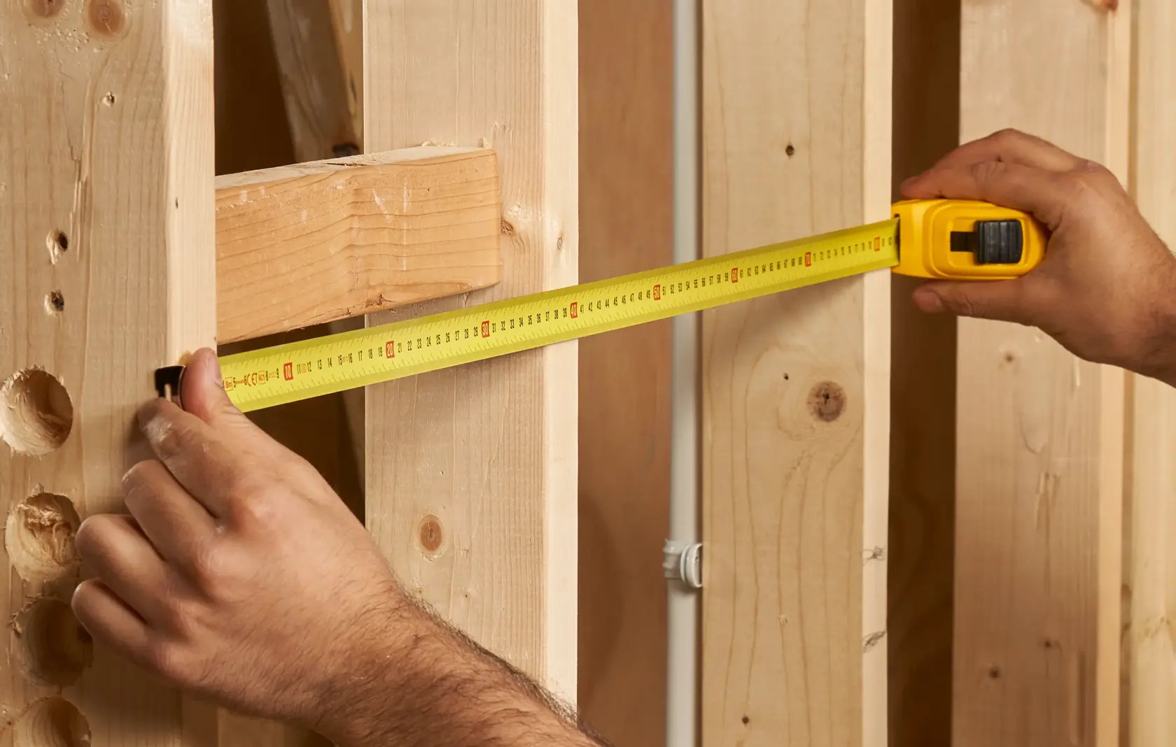 Photo of STANLEY 0-30-457 tape measure in use, measuring distance between wooden studs, close-up angle.
