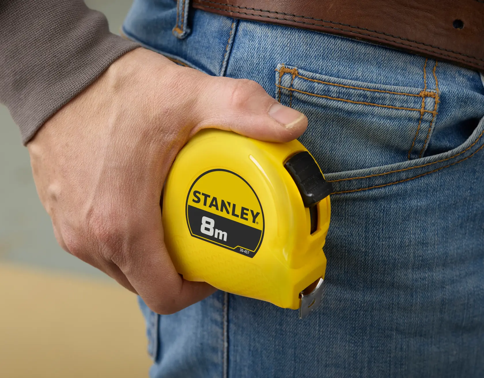 Photo of STANLEY 0-30-457 8m tape measure held in hand next to blue jeans pocket.
