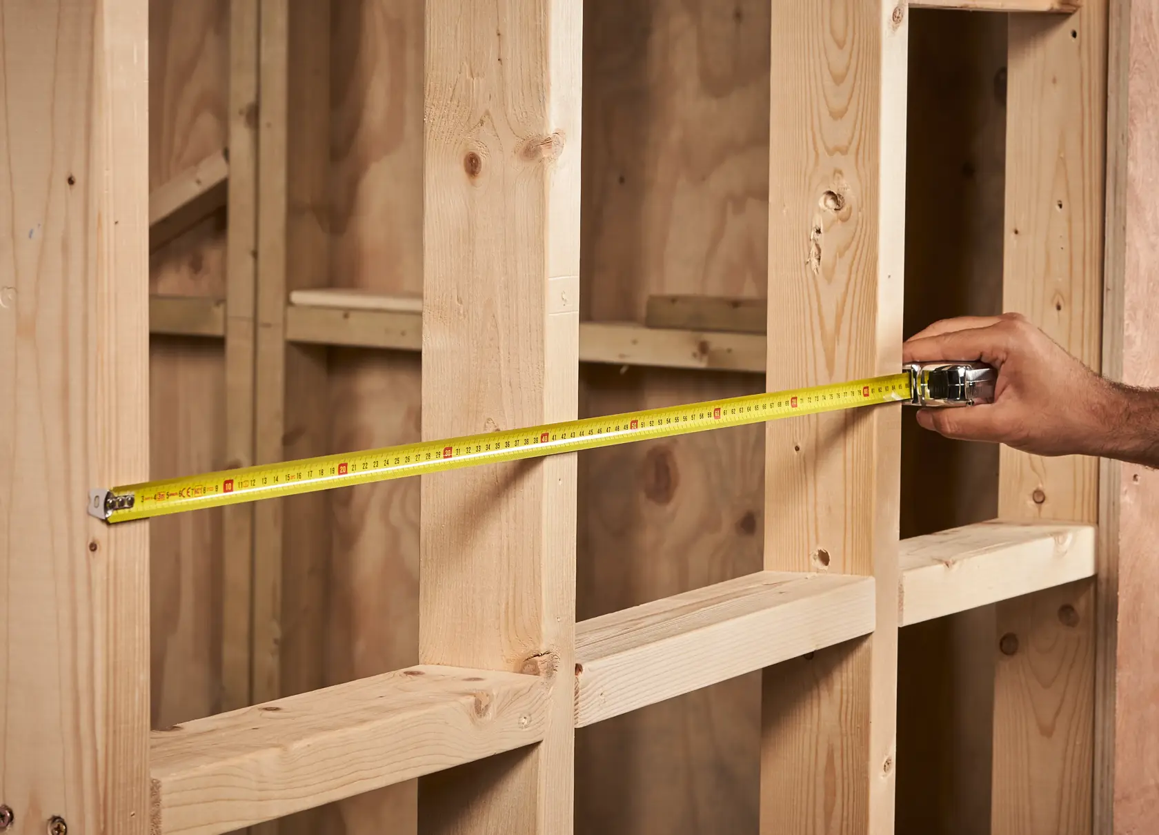 STANLEY 0-33-522 tape measure extended across wooden wall studs, product in use, close-up view.