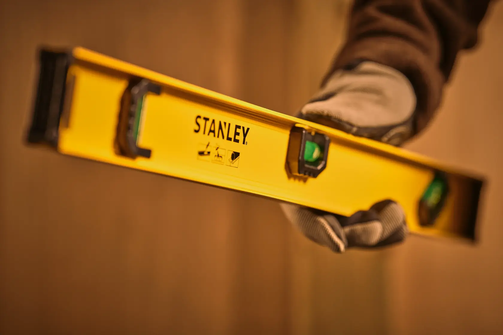 STANLEY 0-42-074 yellow spirit level held by gloved hand, photography close-up at an angle.