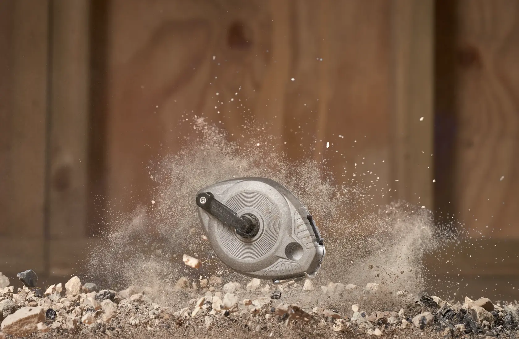 STANLEY 0-47-100 chalk reel photographed in mid-air among dust and gravel, rugged construction site setting.