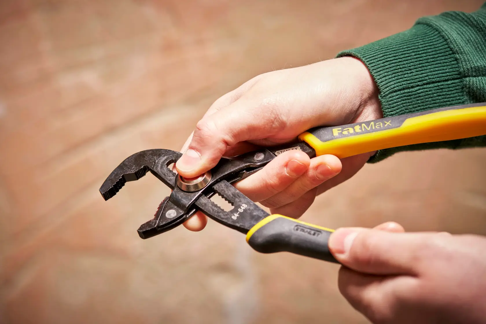STANLEY 0-84-648 water pump pliers, FatMax, black and yellow handles, held in hand.