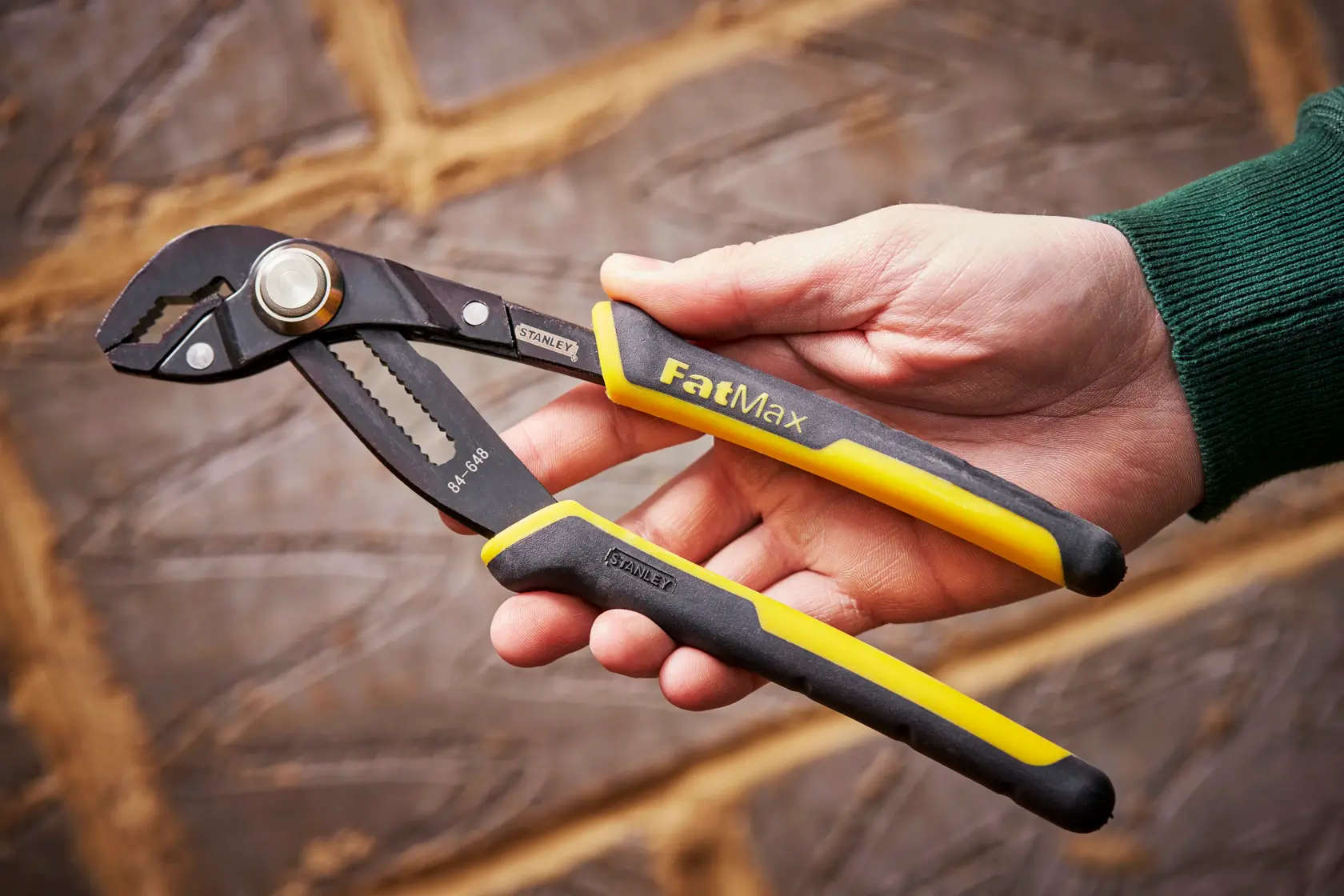 STANLEY 0-84-648 pliers with yellow handles used for plumbing under sink, close-up photography.