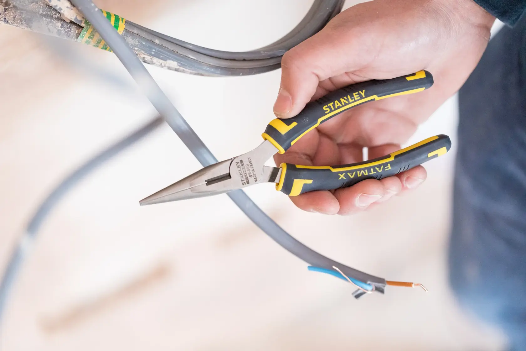 Stanley 0-89-869 FatMax long nose pliers held cutting electrical wire, photography, close-up view.