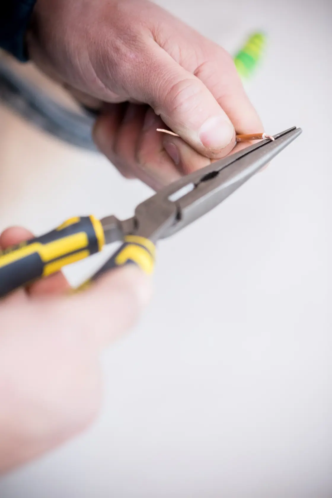 Photo of STANLEY 0-89-870 long nose pliers with yellow and black handle gripping wire, close-up.