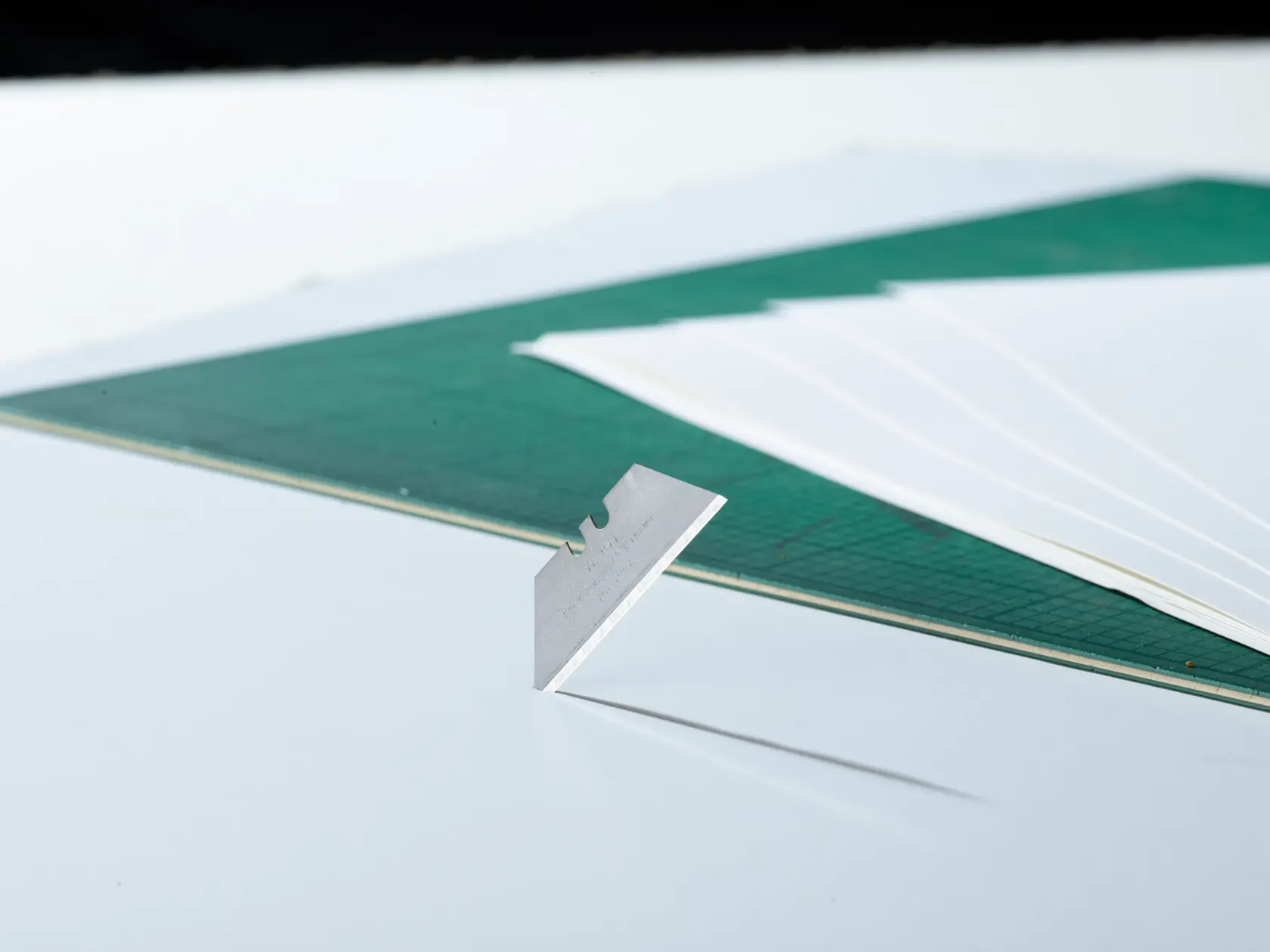 STANLEY 1-11-911 utility blade standing upright, green cutting mat and white sheets in background, side angle photo.