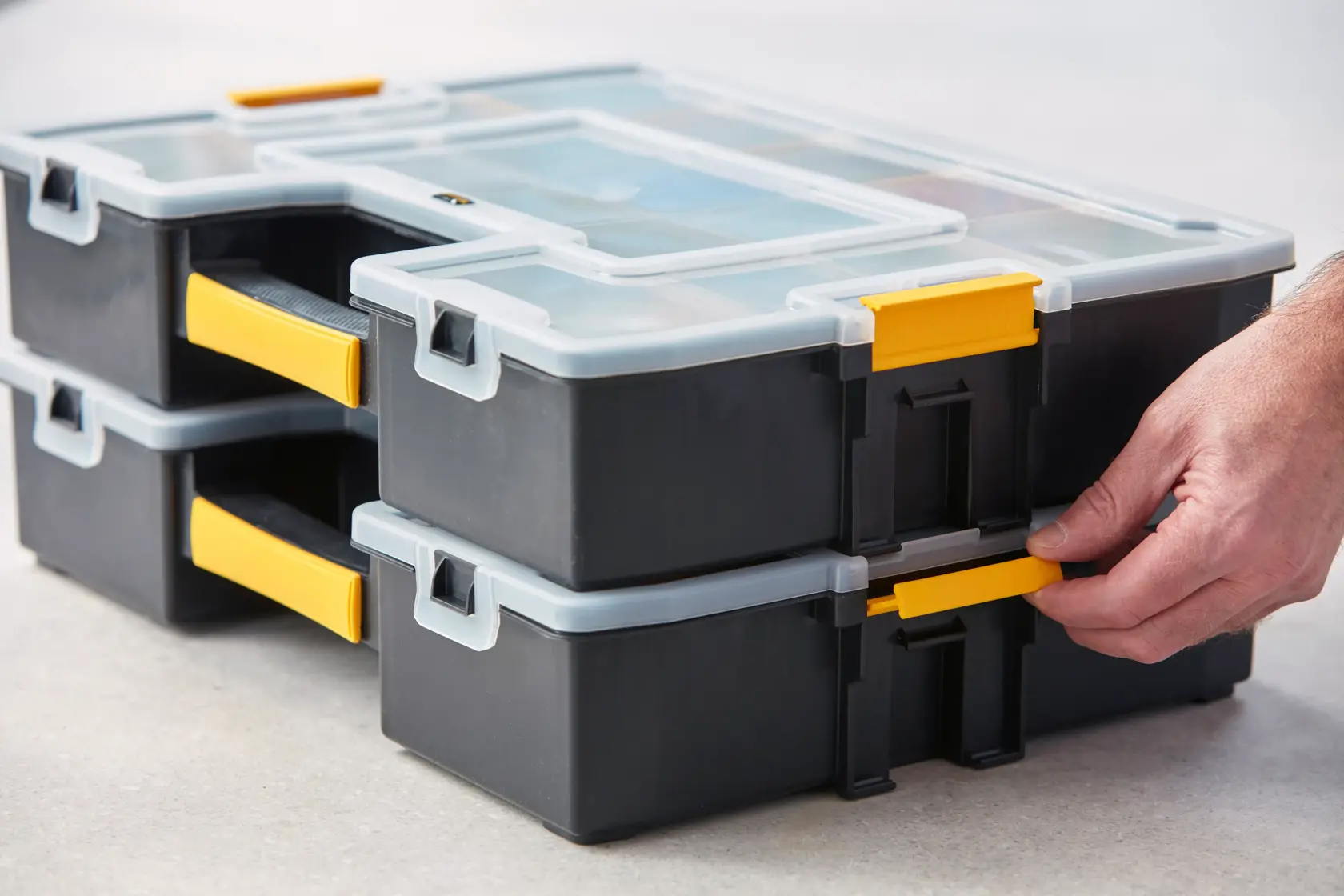 STANLEY 1-94-745 stackable black and yellow organizers with clear lids, close-up side angle, hand adjusting latch.