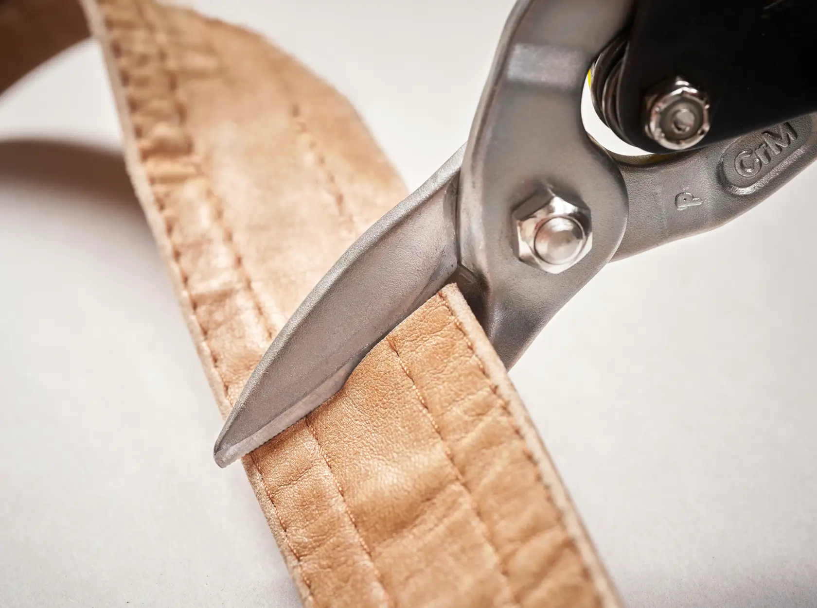 STANLEY 2-14-563 tin snip cutting brown fabric strap, close-up photography.