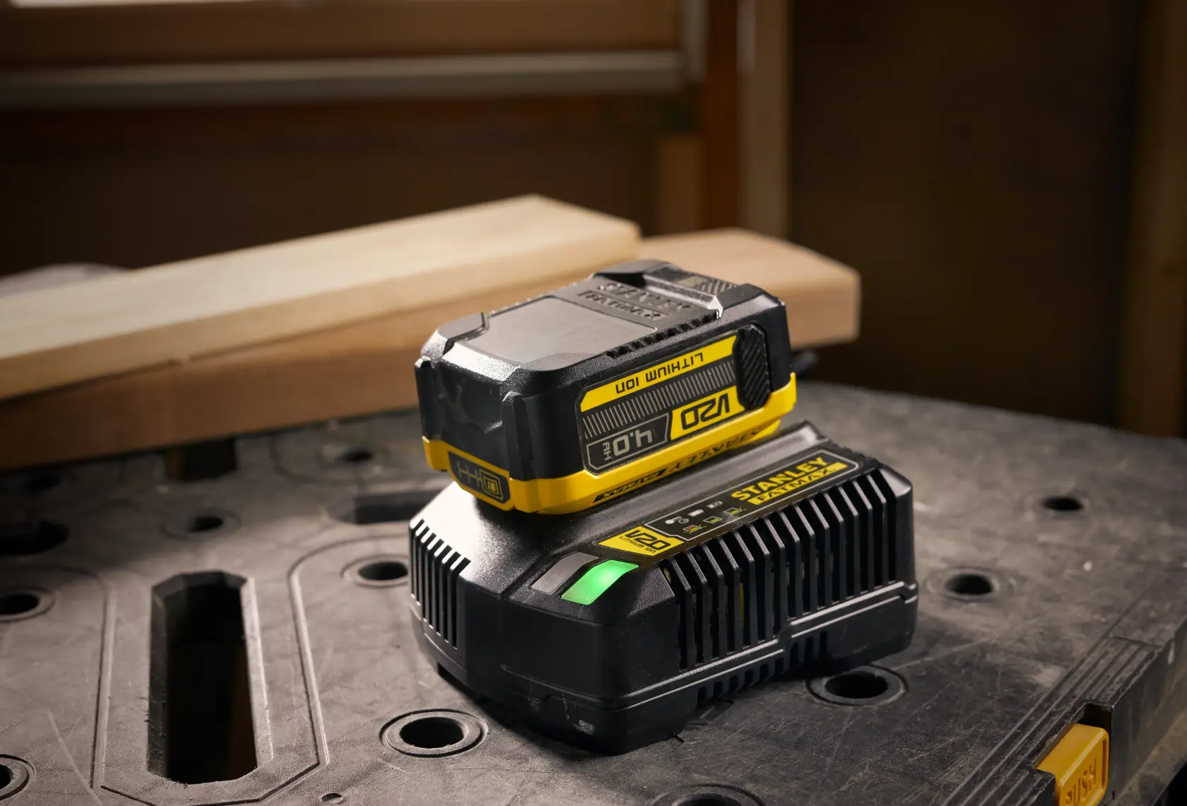 STANLEY SFMCB204 battery and charger, black and yellow, on workshop table, product photography.