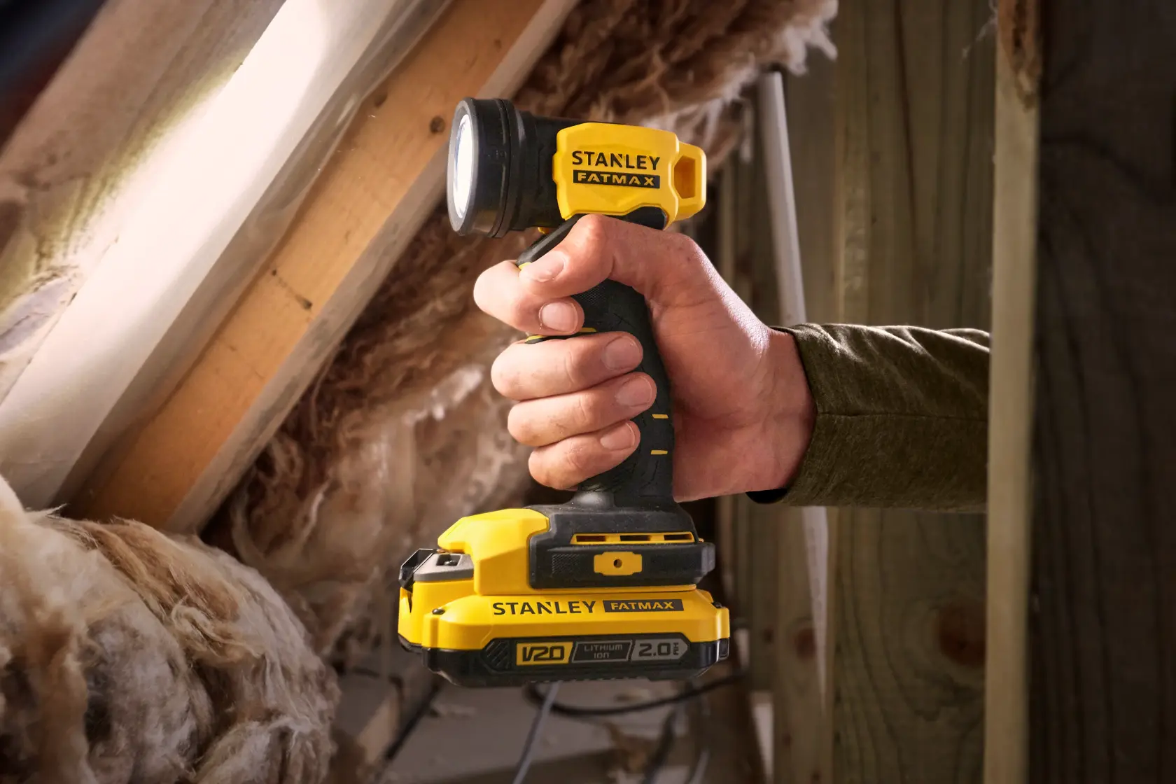 Photo of STANLEY SFMCL020B cordless yellow and black work light held in hand, shown in attic setting.