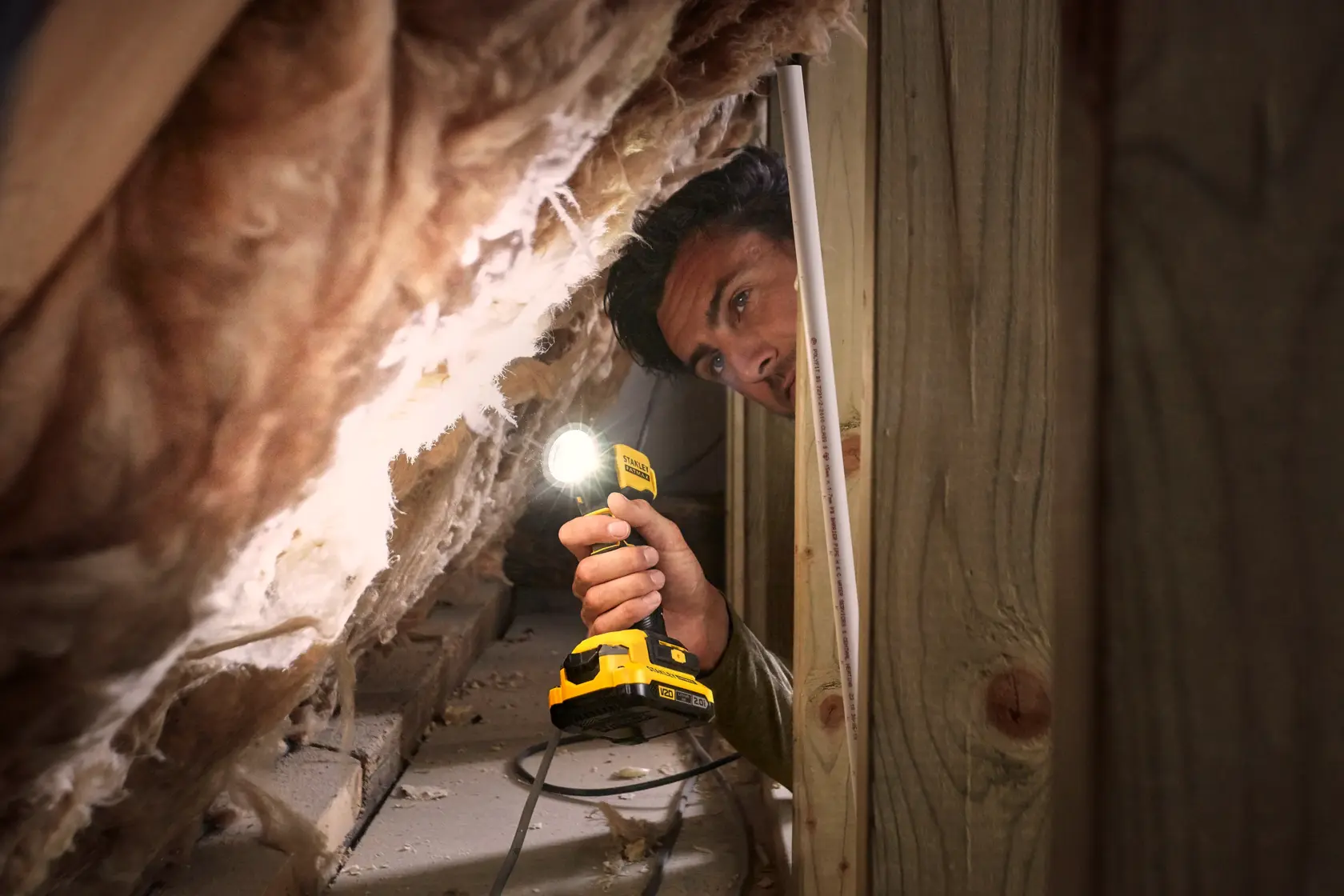 STANLEY SFMCL020B cordless work light used in an attic space, yellow body illuminates insulation.