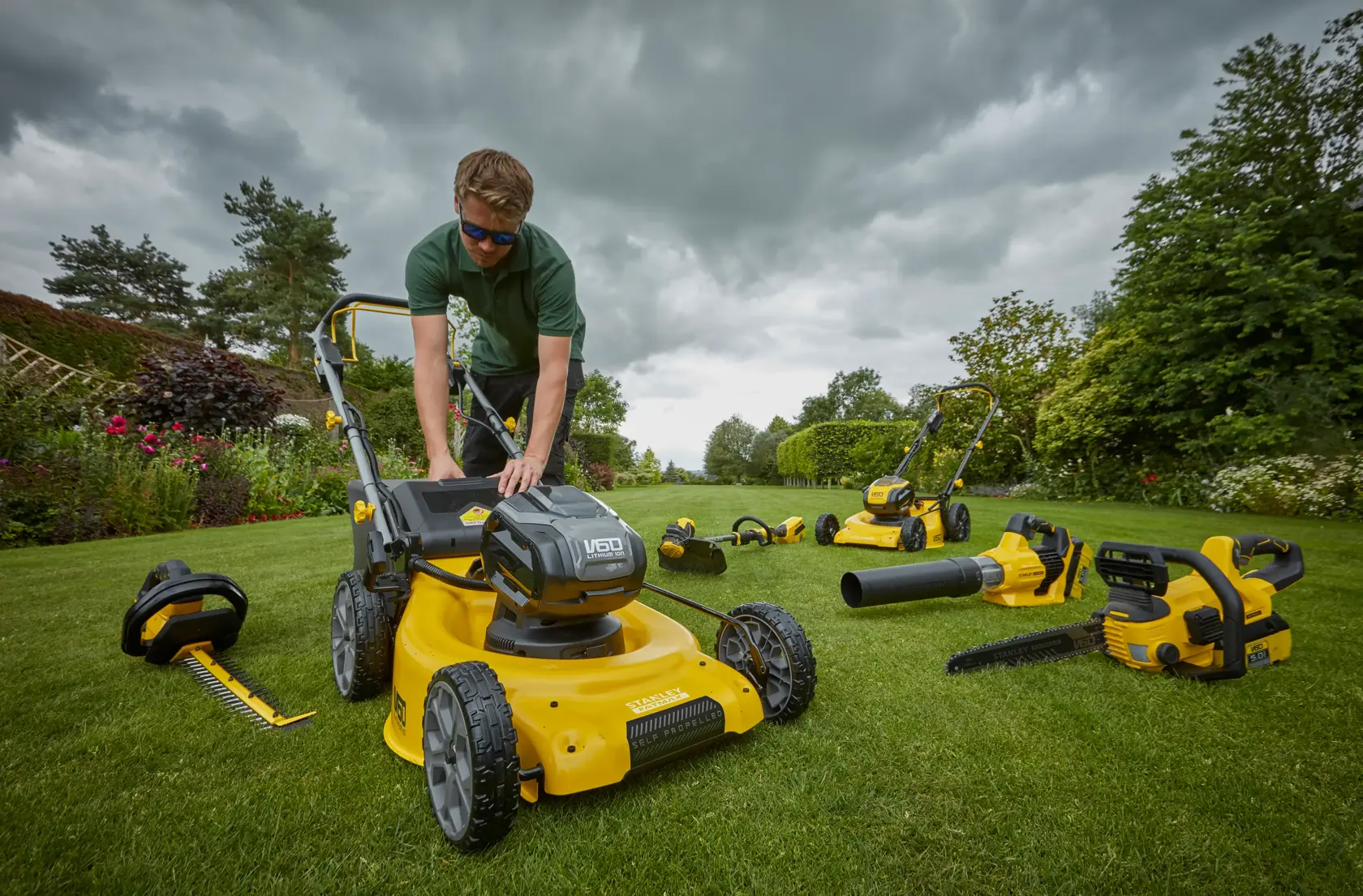 Photo of STANLEY SFMCMW2653B lawn mower with cordless garden tools on grass, outdoor setting.