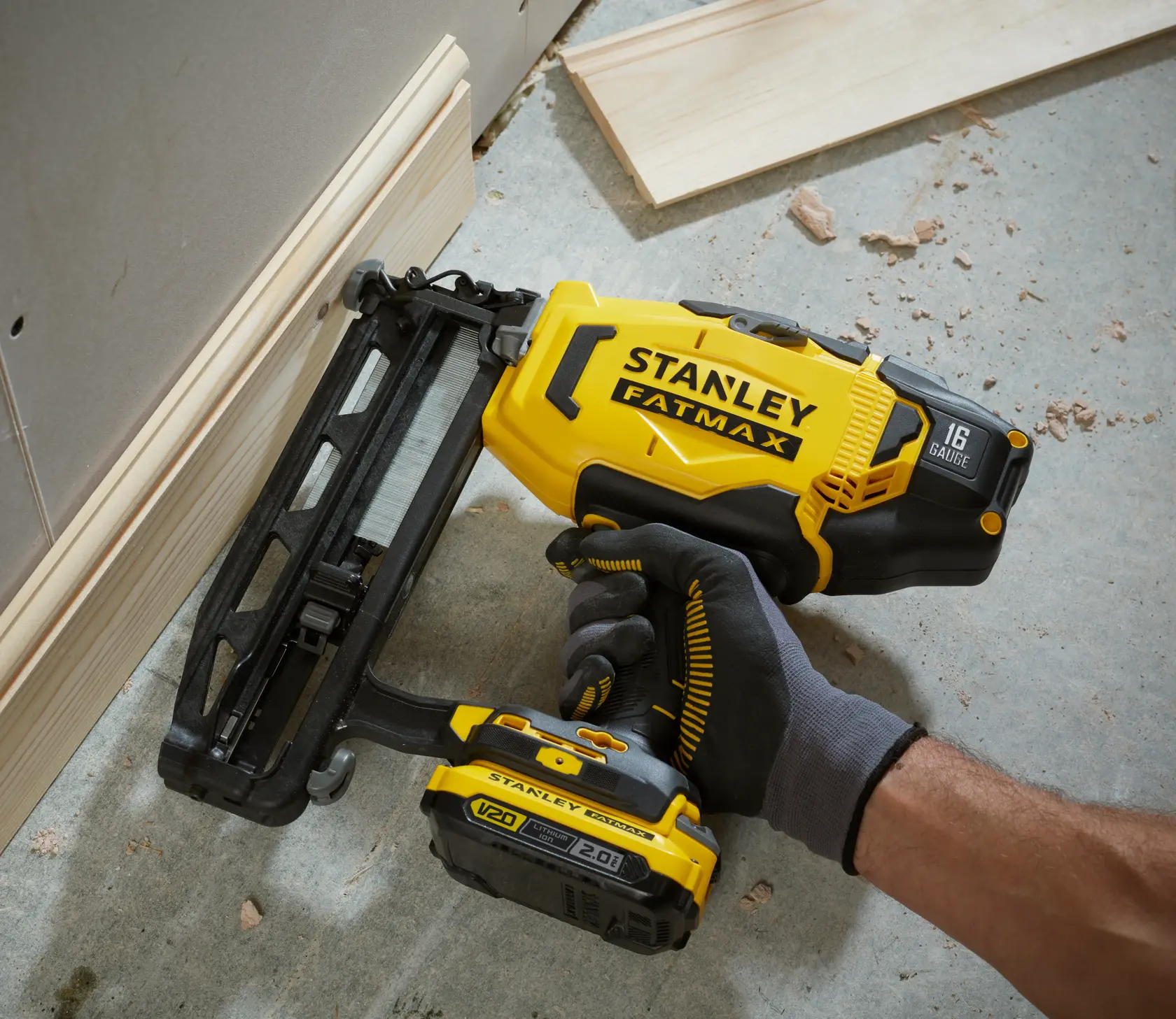 Photo of STANLEY SFMCN616B cordless nail gun in use, yellow and black, close-up angled view.