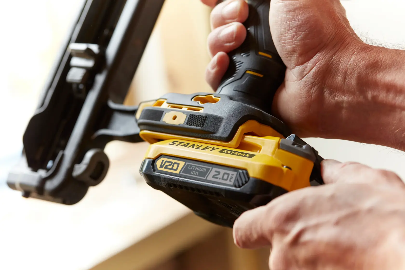 Photo of STANLEY SFMCN616B cordless nailer with V20 lithium-ion battery, close-up view in hand.