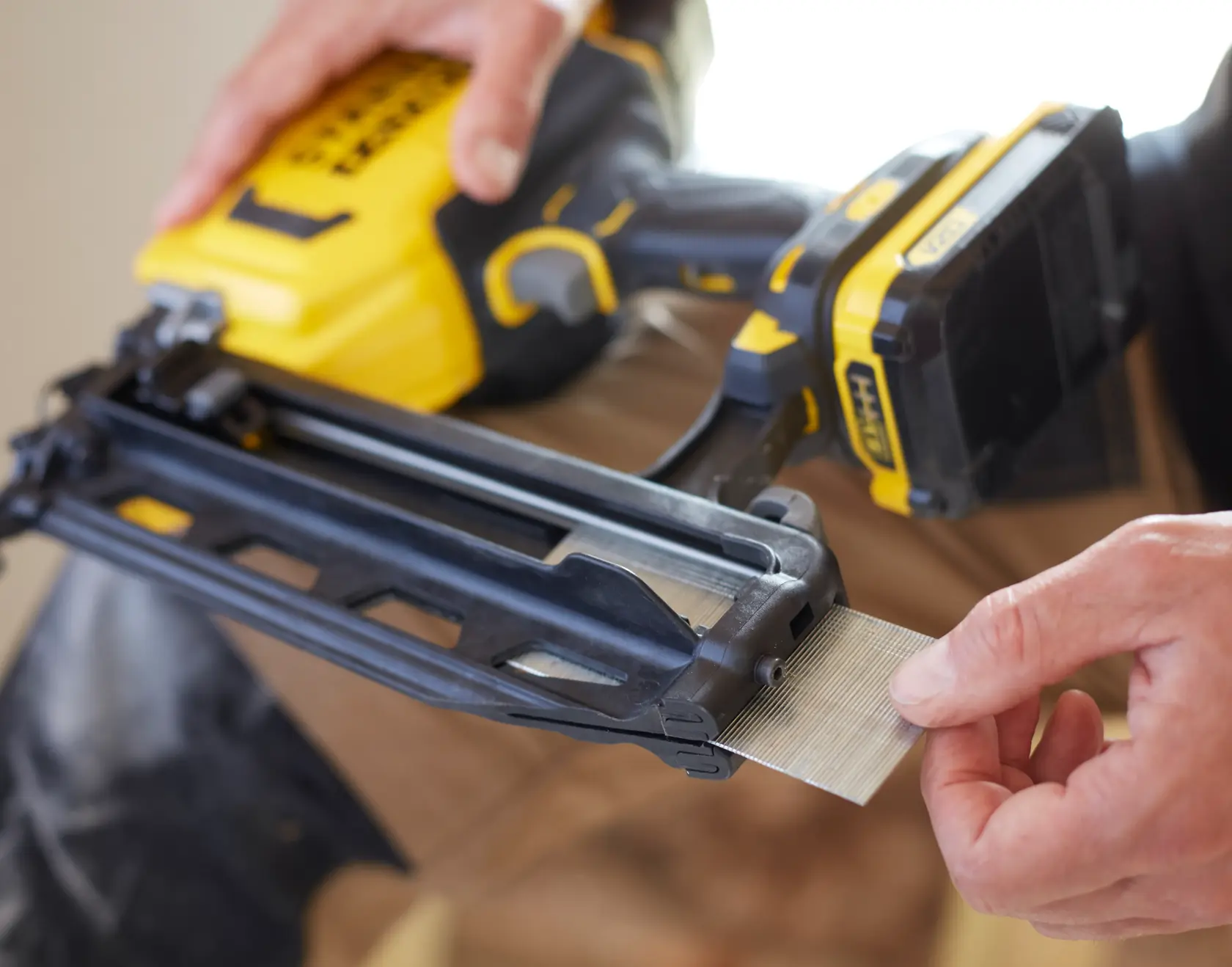 STANLEY SFMCN616B nailer photo, close-up of hand loading nails into yellow and black cordless tool.