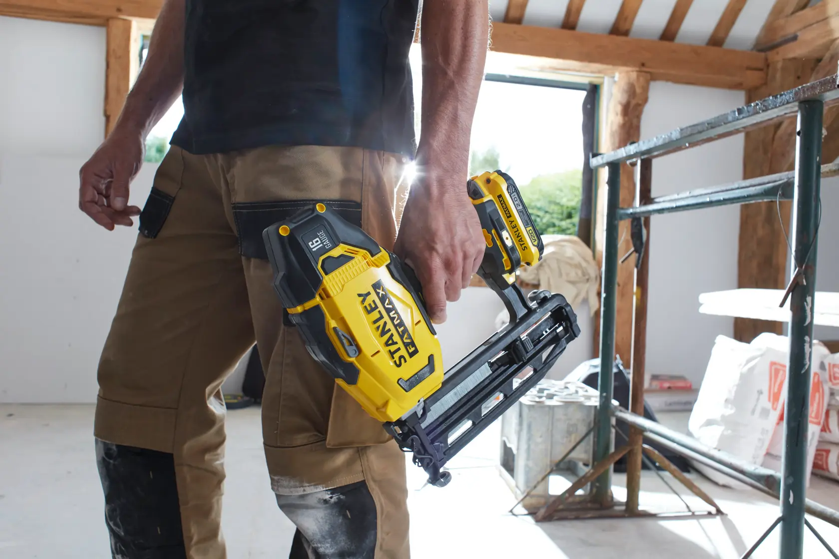 Photo of STANLEY SFMCN616B cordless nailer held by a worker in construction setting.