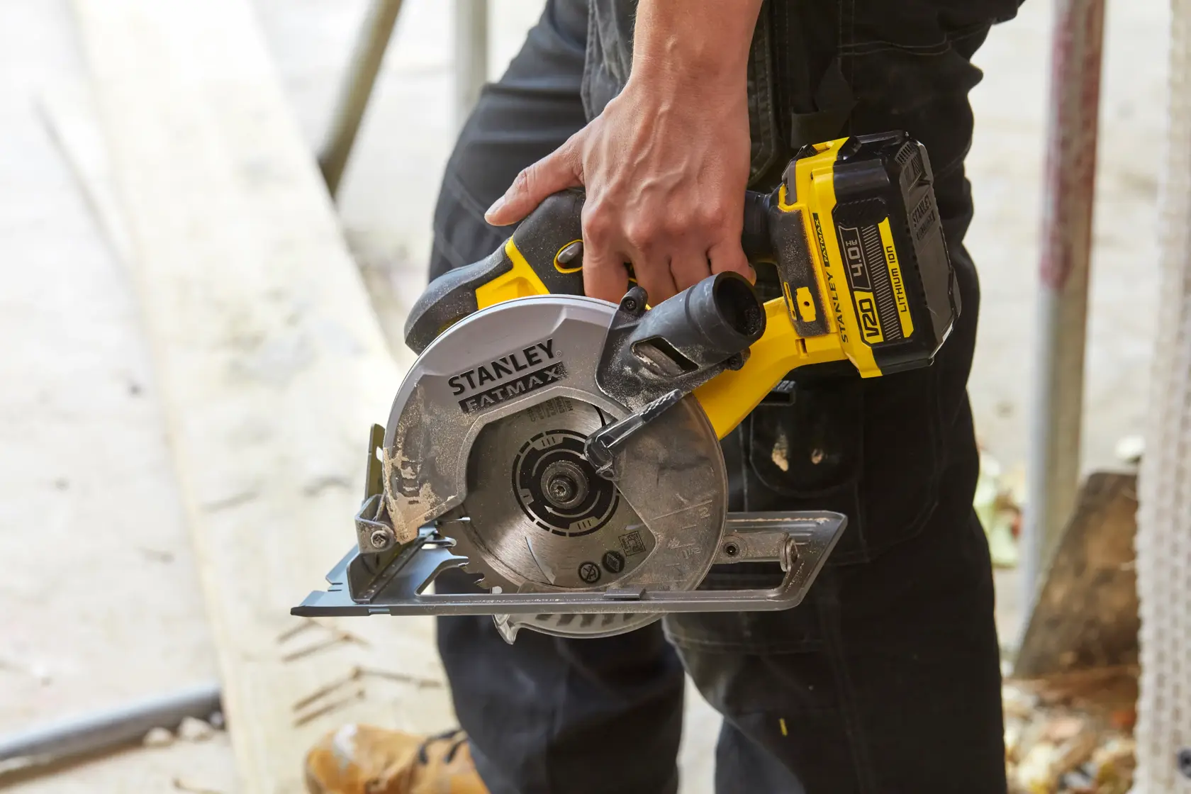 STANLEY SFMCS500B cordless circular saw held by person, yellow and black design, construction context.