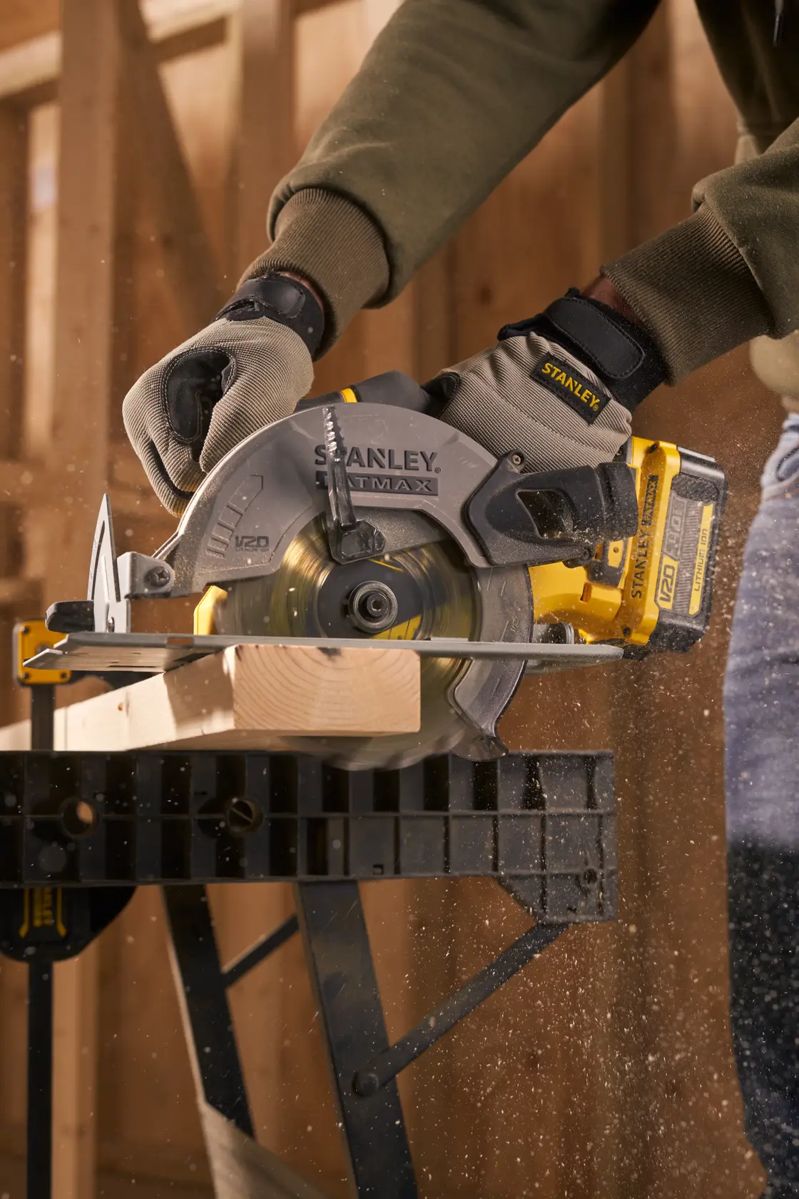 Stanley SFMCS500M1K circular saw cutting wood in workshop, close-up photo with gloves and sawdust.