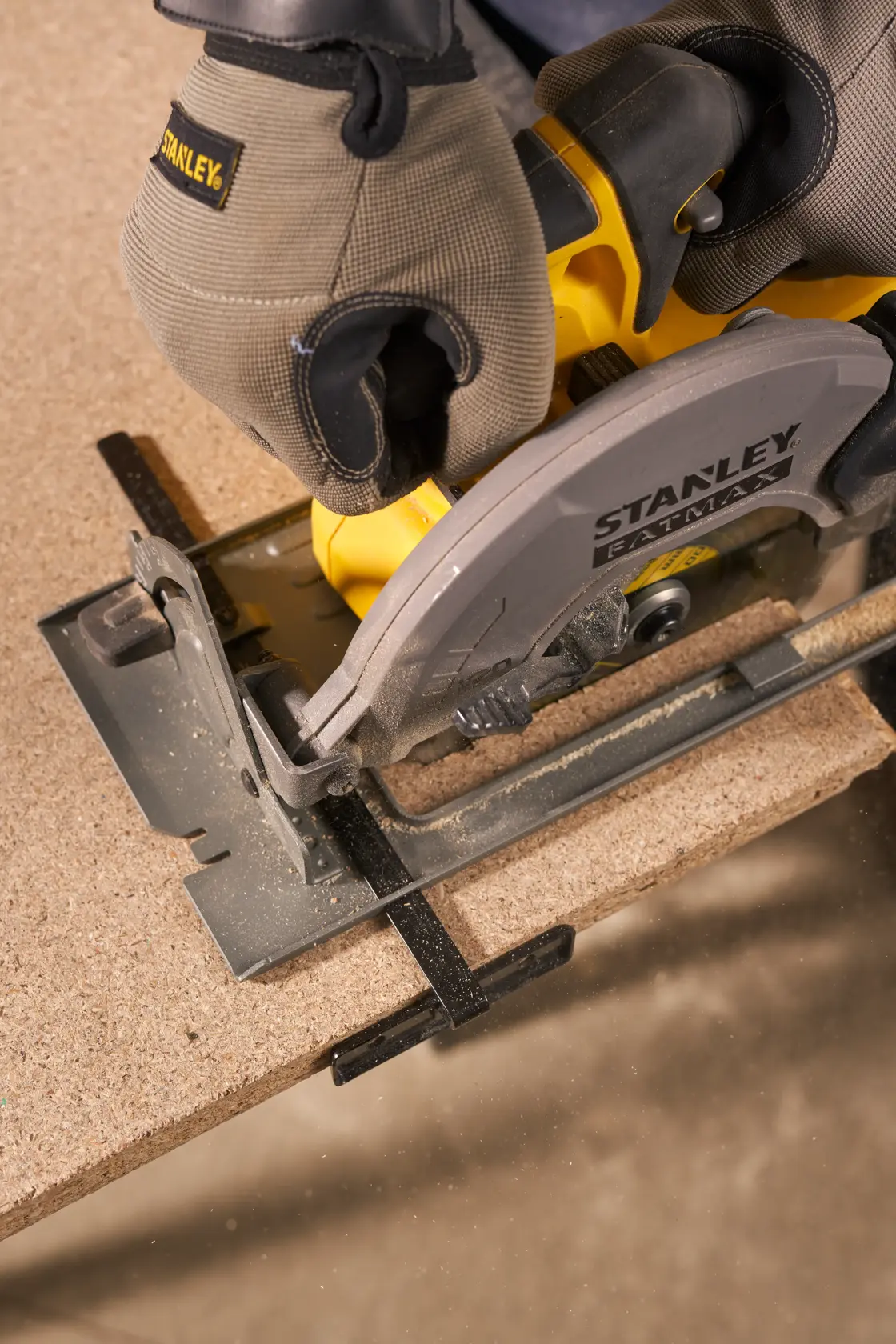 Photo of STANLEY SFMCS500M1K circular saw cutting wood, close-up view showing safety gloves in use.