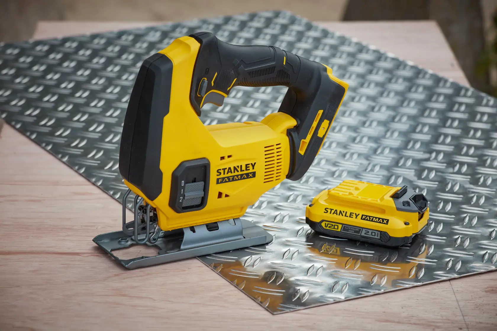 Stanley FatMax cordless jigsaw and battery on metal sheet, suitable for cutting in DIY and professional projects.