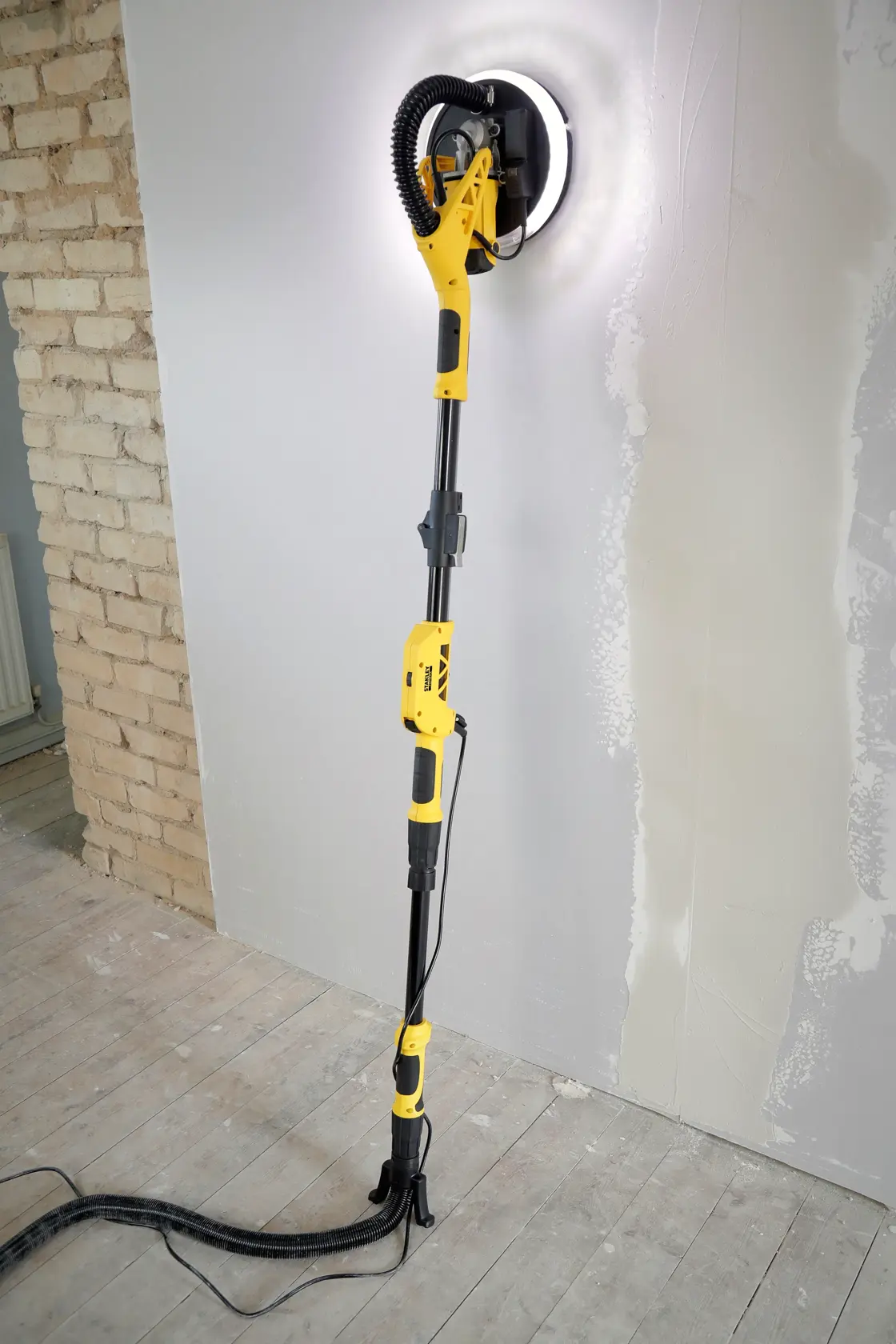 STANLEY SFMEE500S wall sander with LED light, telescopic handle, sanding plaster wall, side view.