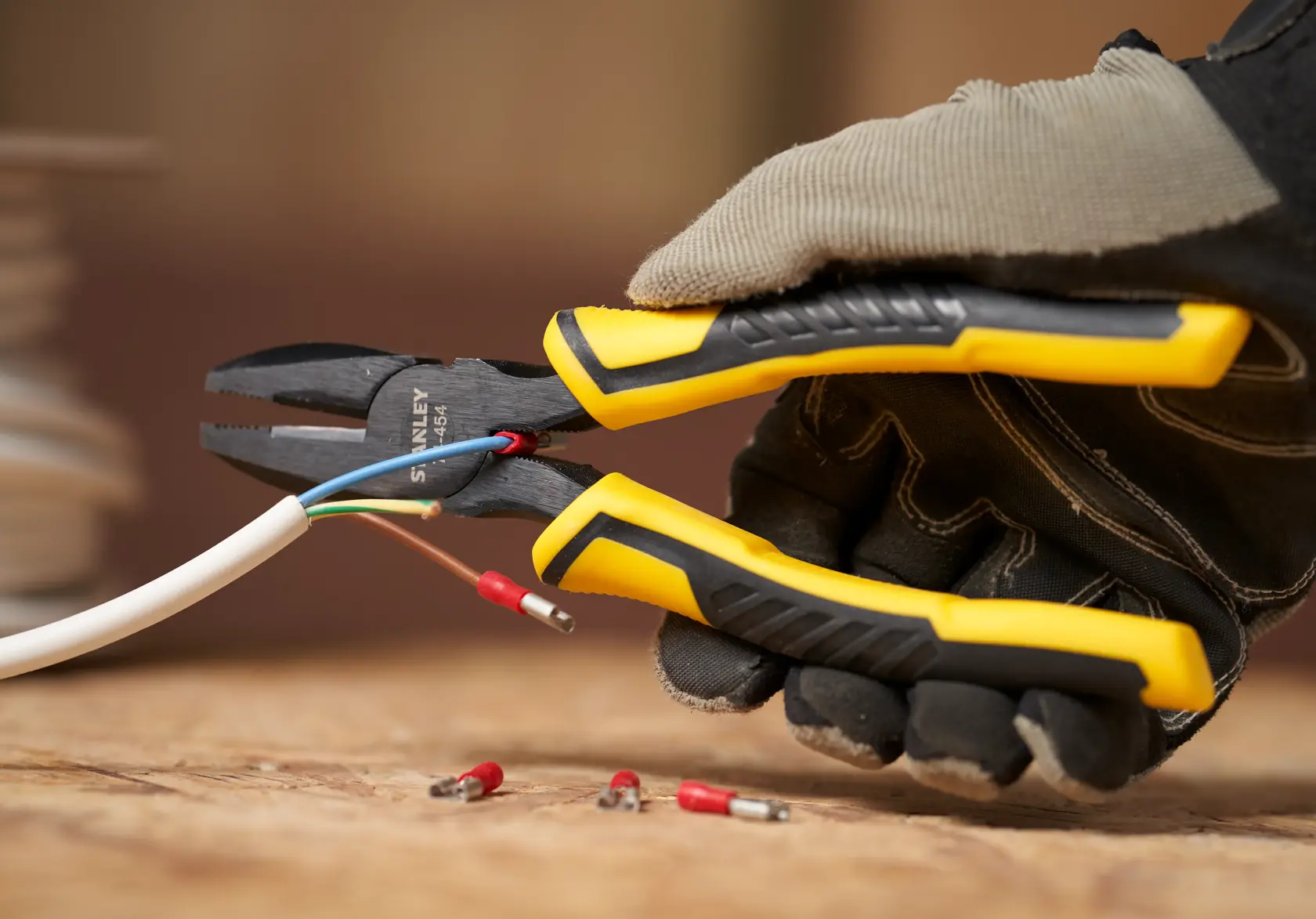 STANLEY STHT0-74367 pliers with yellow and black grip, cutting electrical wire, close-up view.