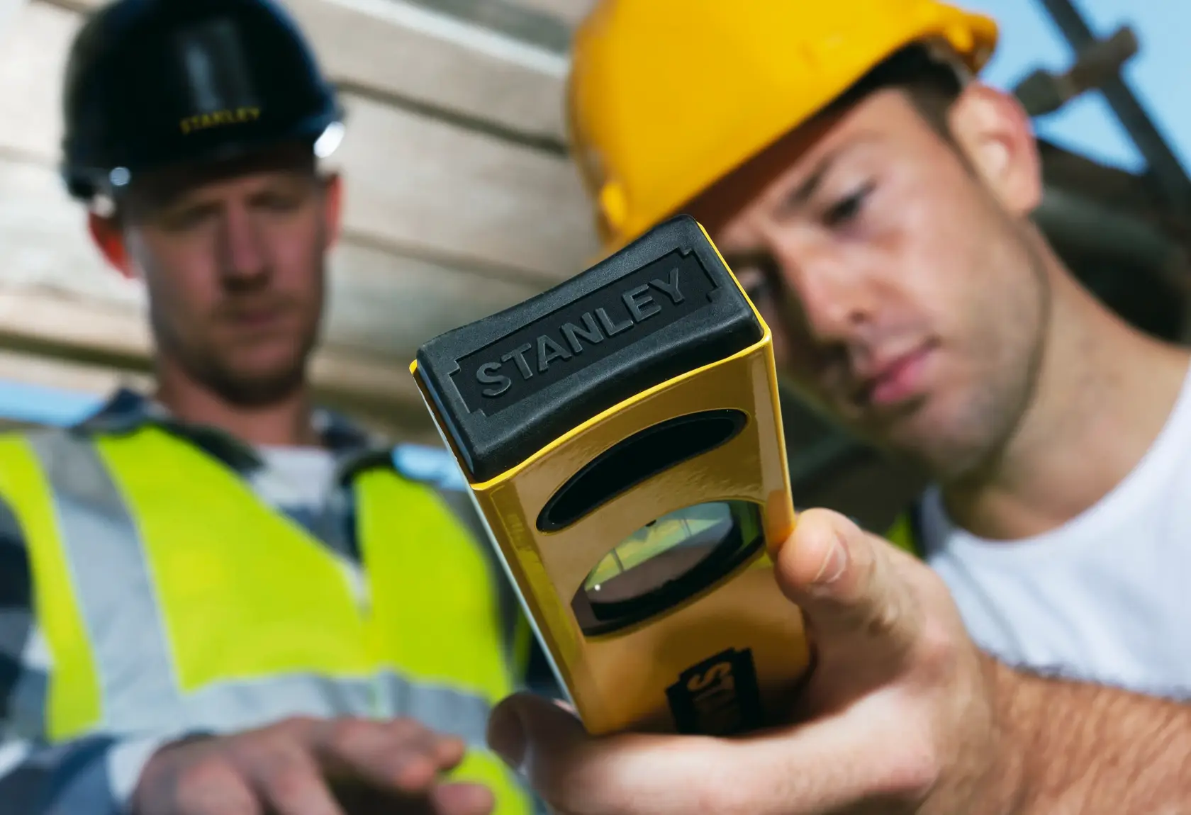 Photo of STANLEY STHT1-43102 level tool in use at construction site, close-up on yellow and black tool.