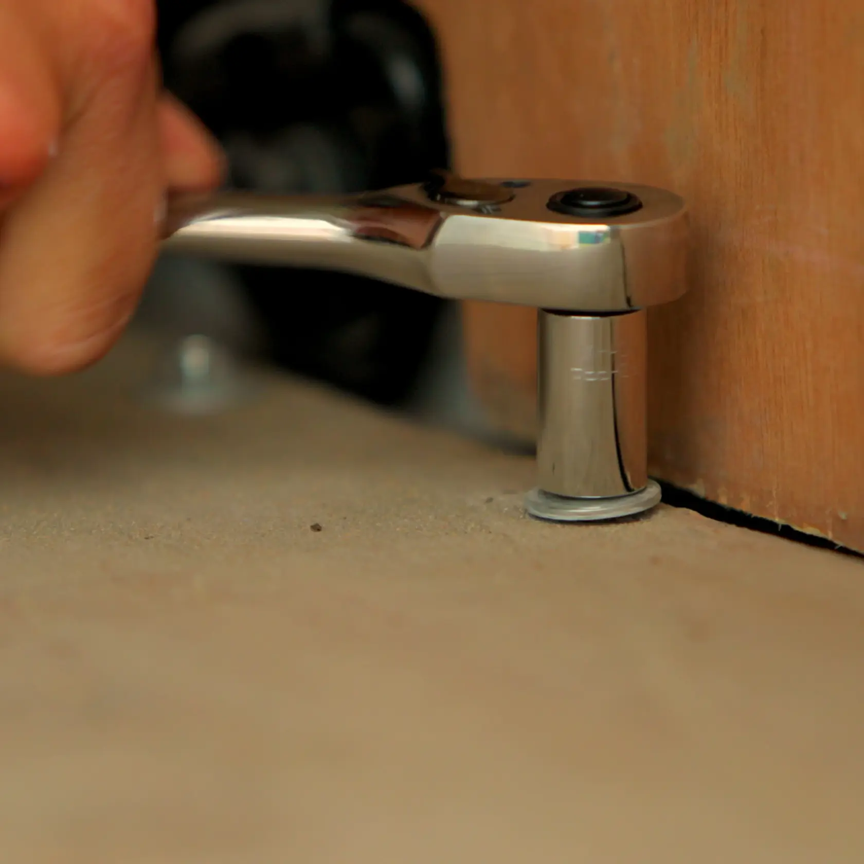 STANLEY STMT0-74864 ratchet wrench in use, close-up on socket fitting against a bolt near a wooden surface.