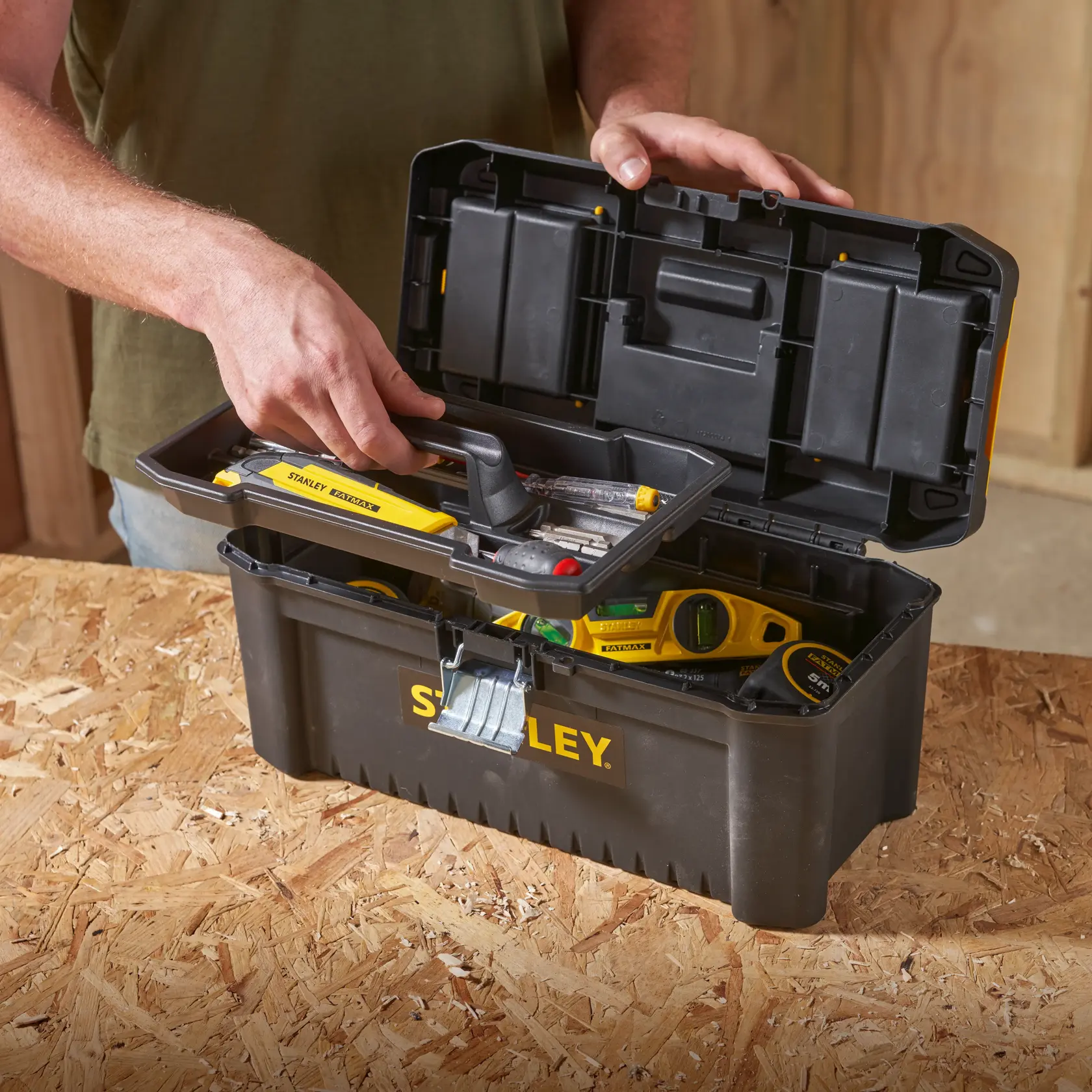 STANLEY STST1-75518-KR black toolbox with tray, filled with tools, on wooden surface.