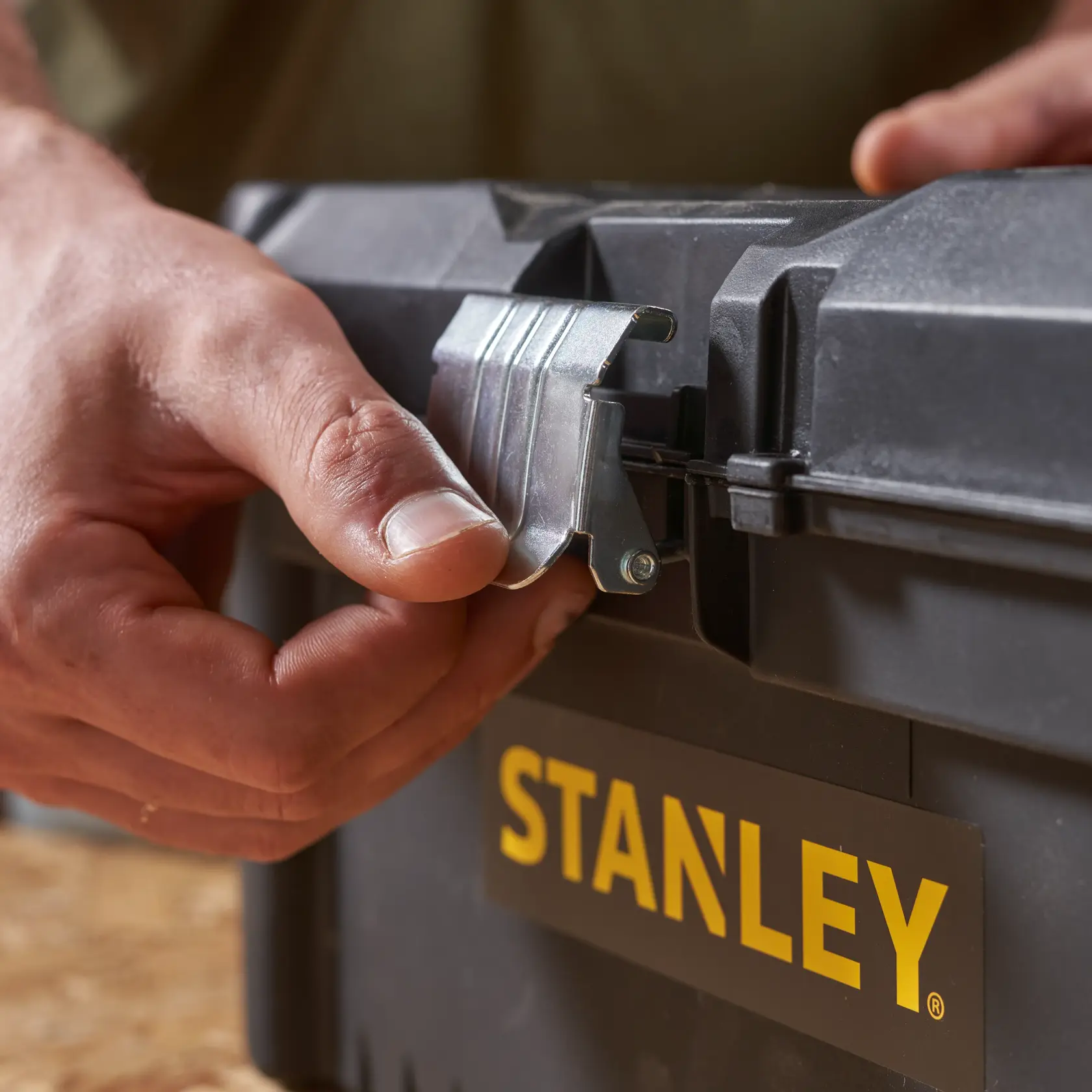 STANLEY STST1-75518-KR toolbox close-up, hand opening metal latch, black case, yellow logo.