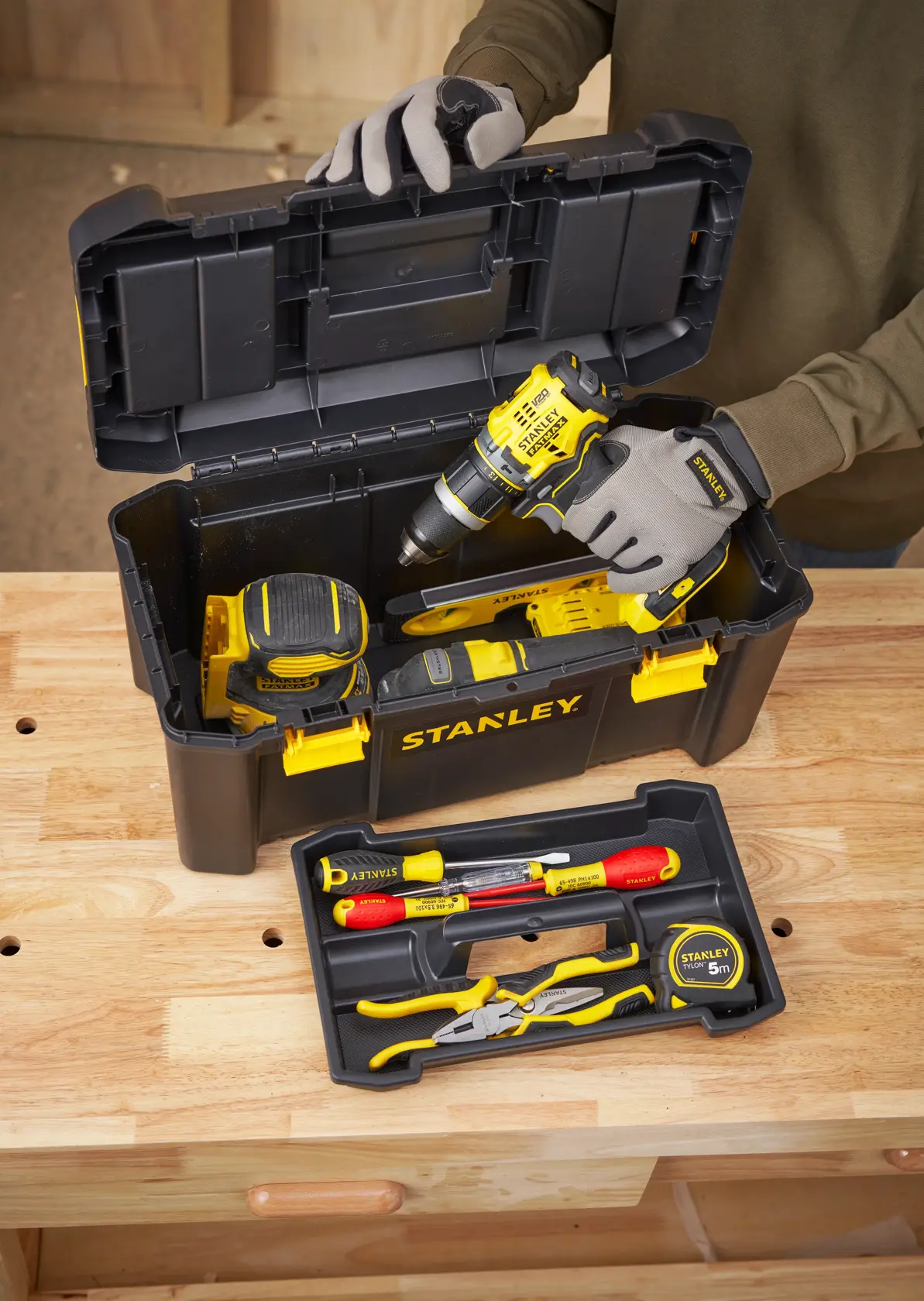 STANLEY STST1-75520 toolbox with various hand tools and a drill, photo from above on workbench.