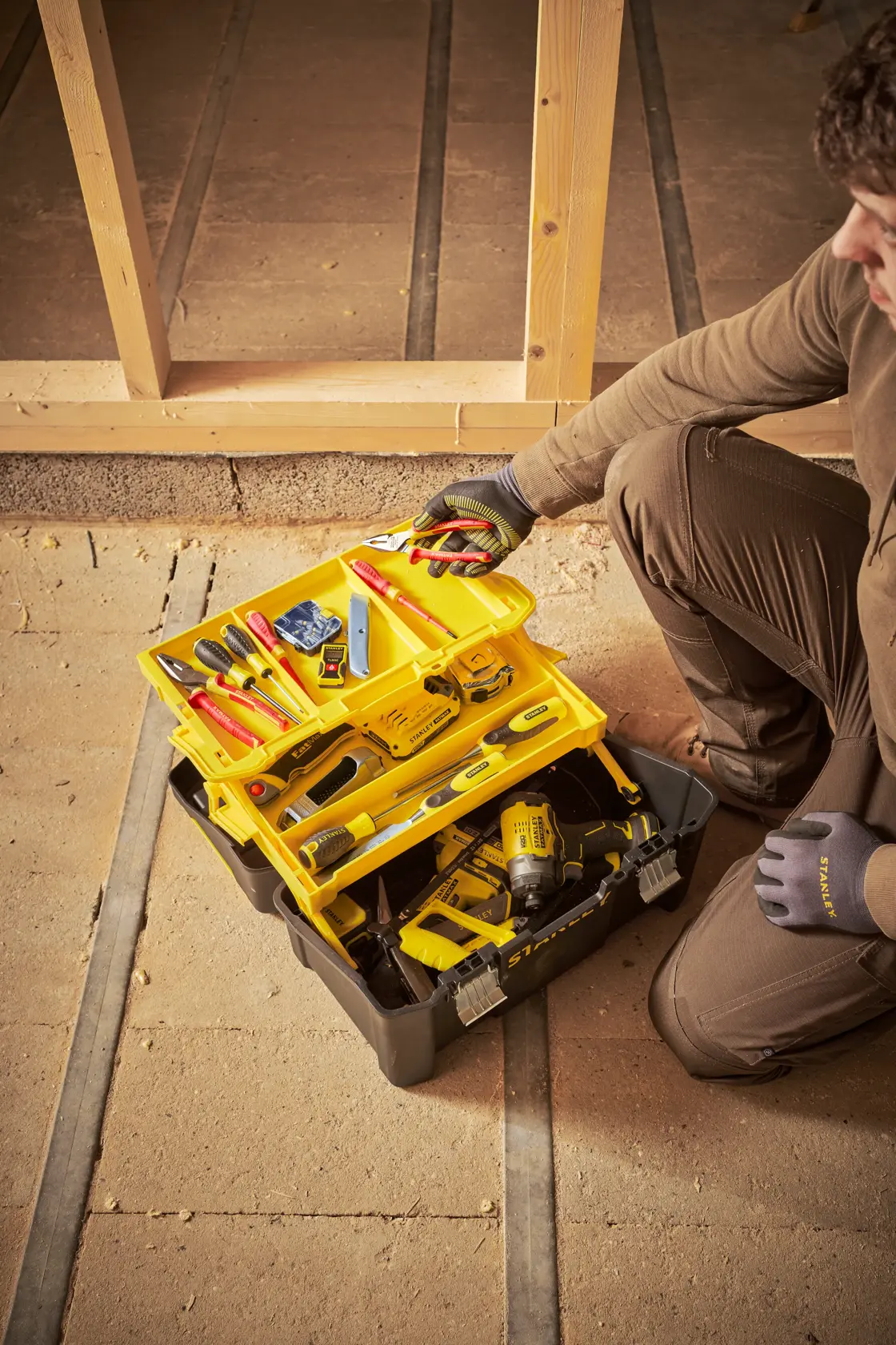 STANLEY STST83397-1 tool box with yellow trays and assorted tools, photo of product in jobsite setting.