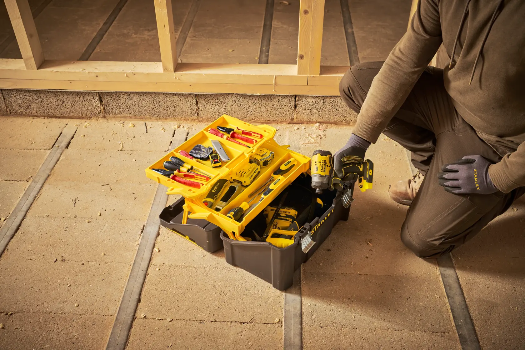 STANLEY STST83397-1 tool box open with assorted tools and drill in construction setting.