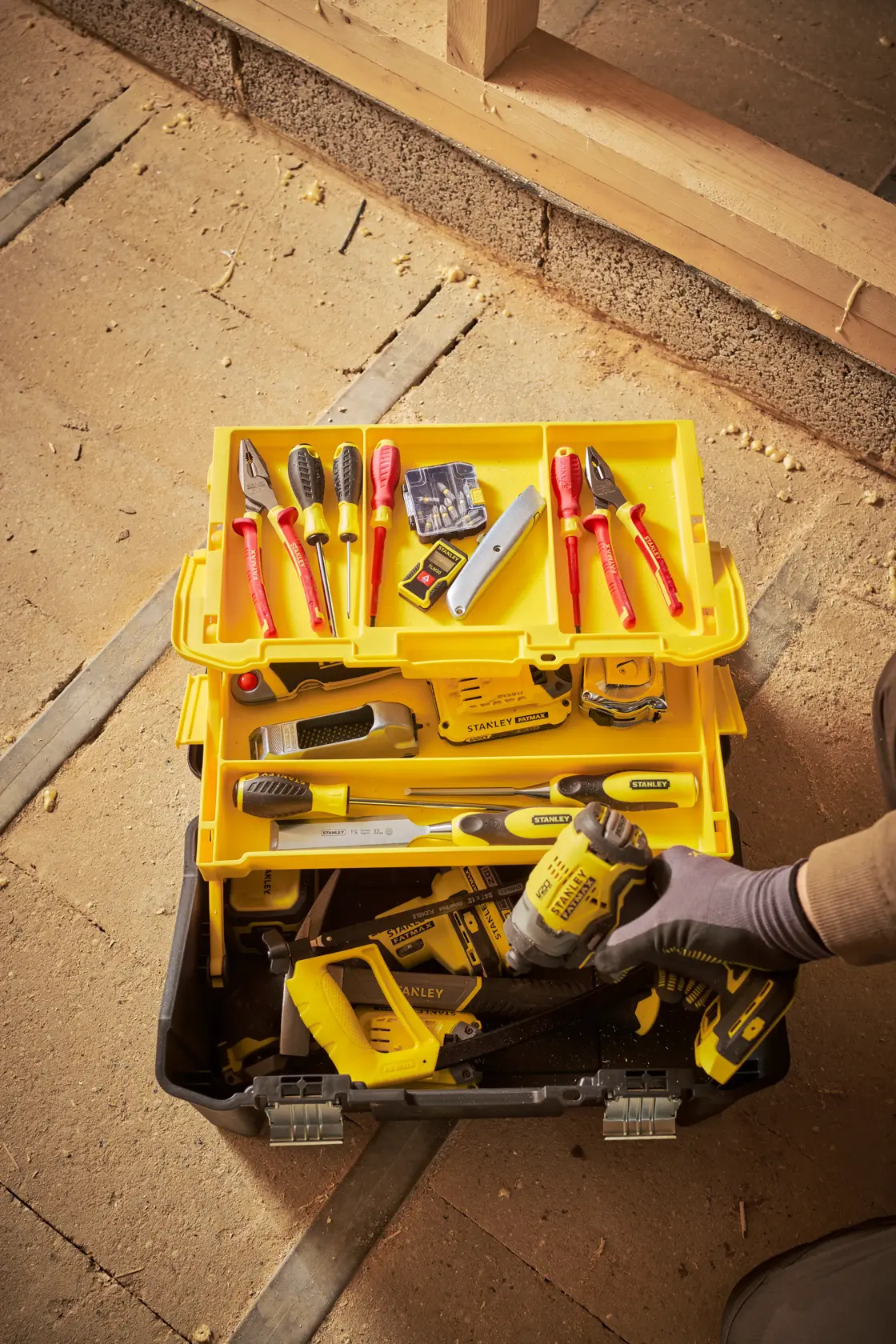 Stanley STST83397-1 toolbox with assorted hand tools, yellow tray, and power tool, top-down view.