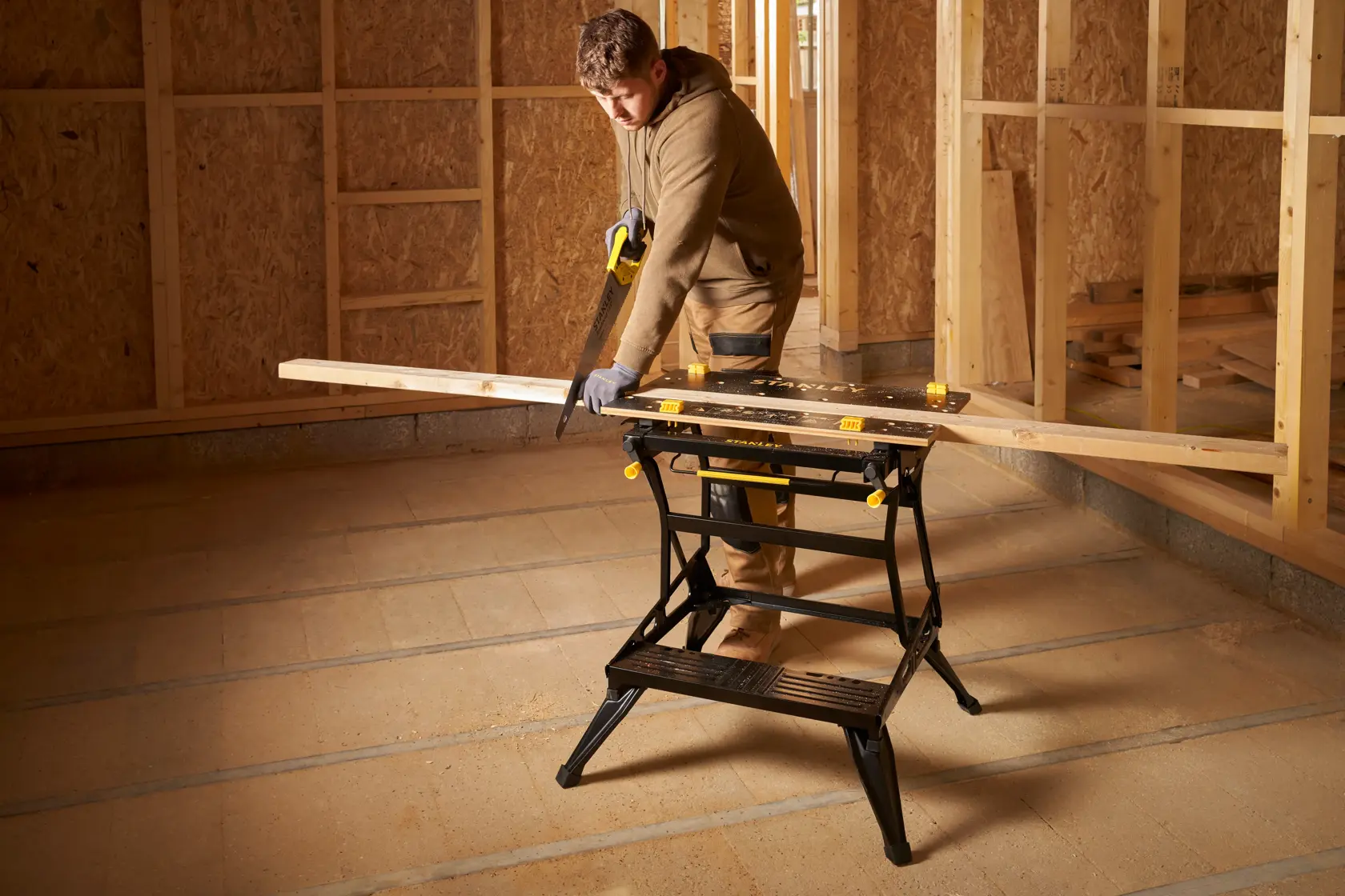 STANLEY STST83800-1 sawhorse used for cutting wood, shown in a construction site setting.