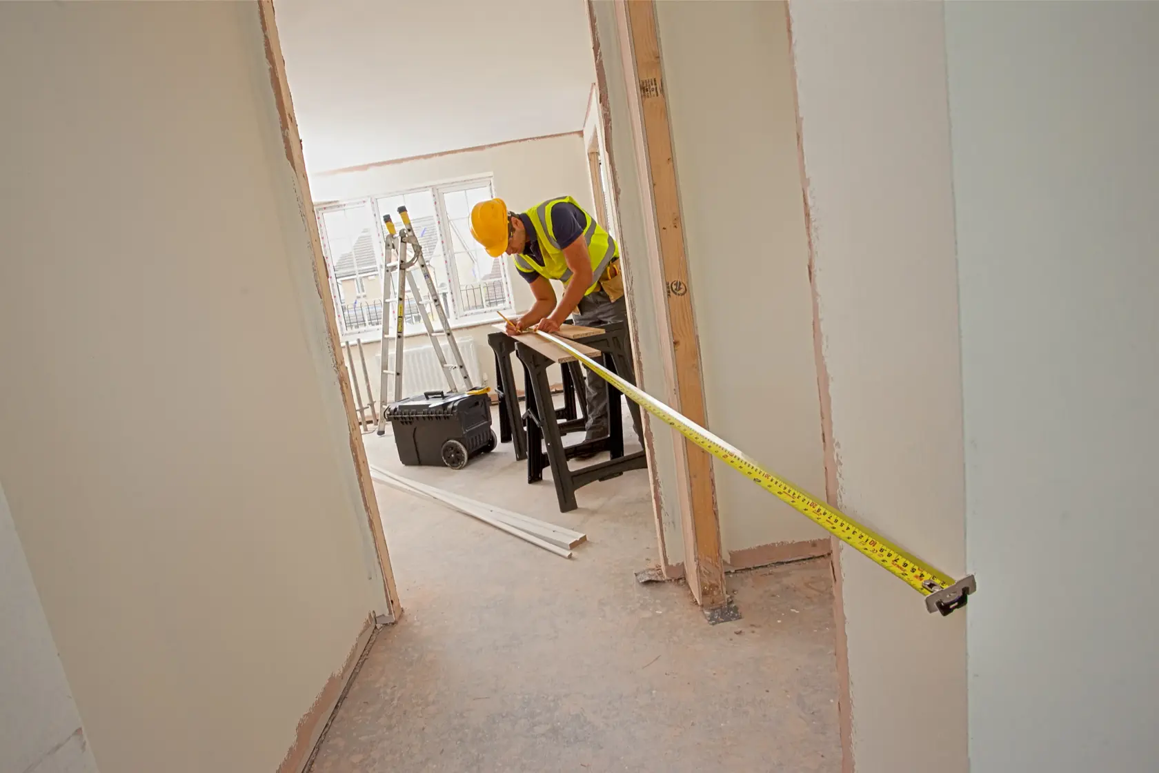 STANLEY XTHT0-33501 tape measure used by worker in construction site, yellow color, extended across doorway.