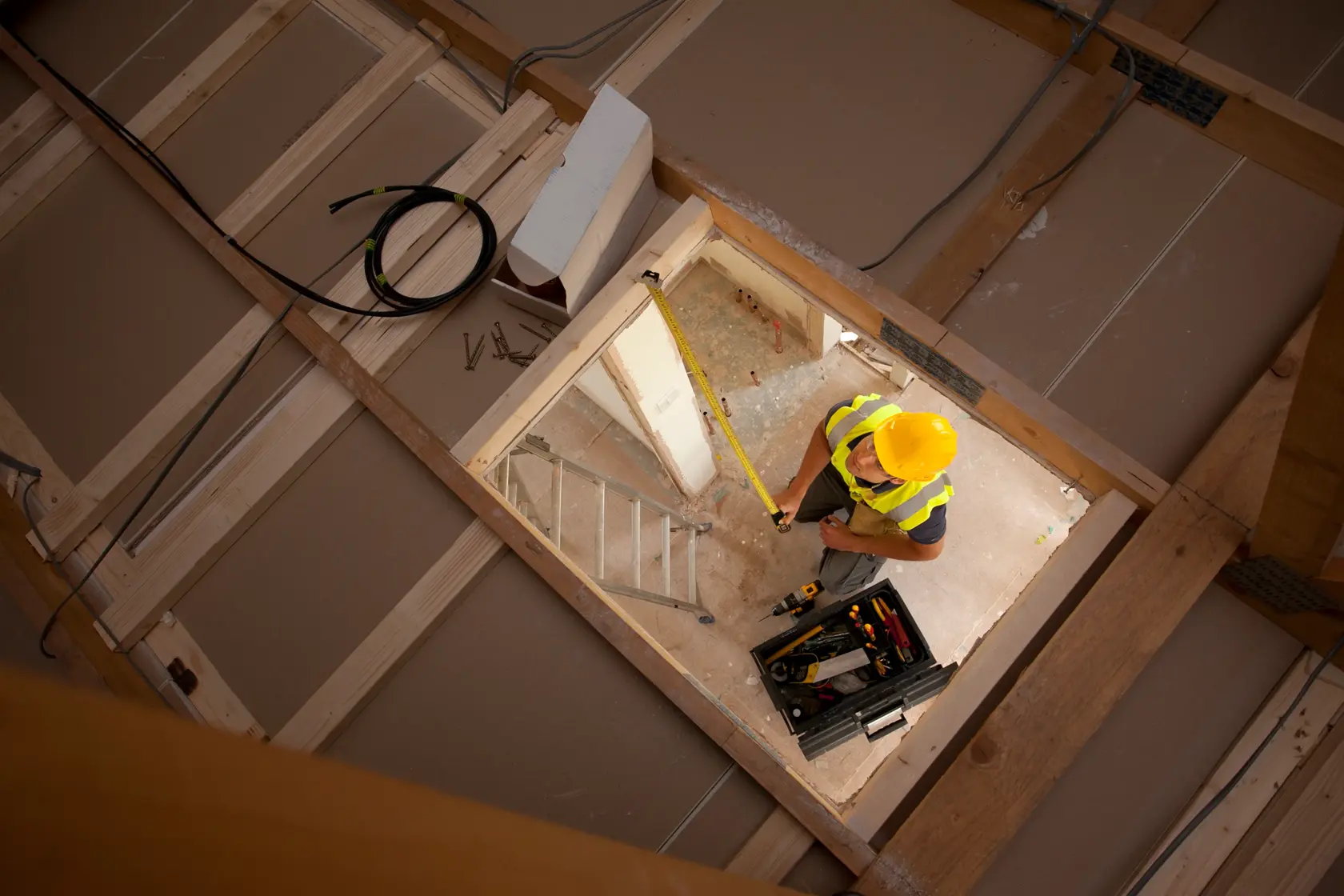 STANLEY XTHT0-33501 measuring tape used by worker in construction area, photographed from above.