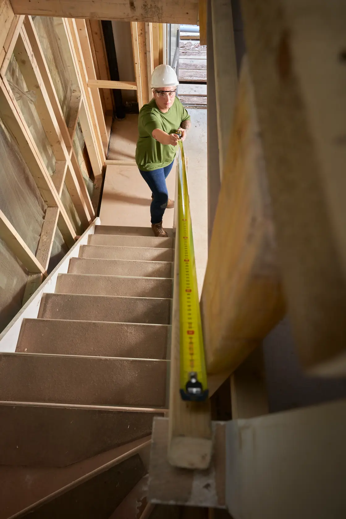 STANLEY XTHT0-33501 tape measure used on staircase by person wearing safety gear, construction setting.