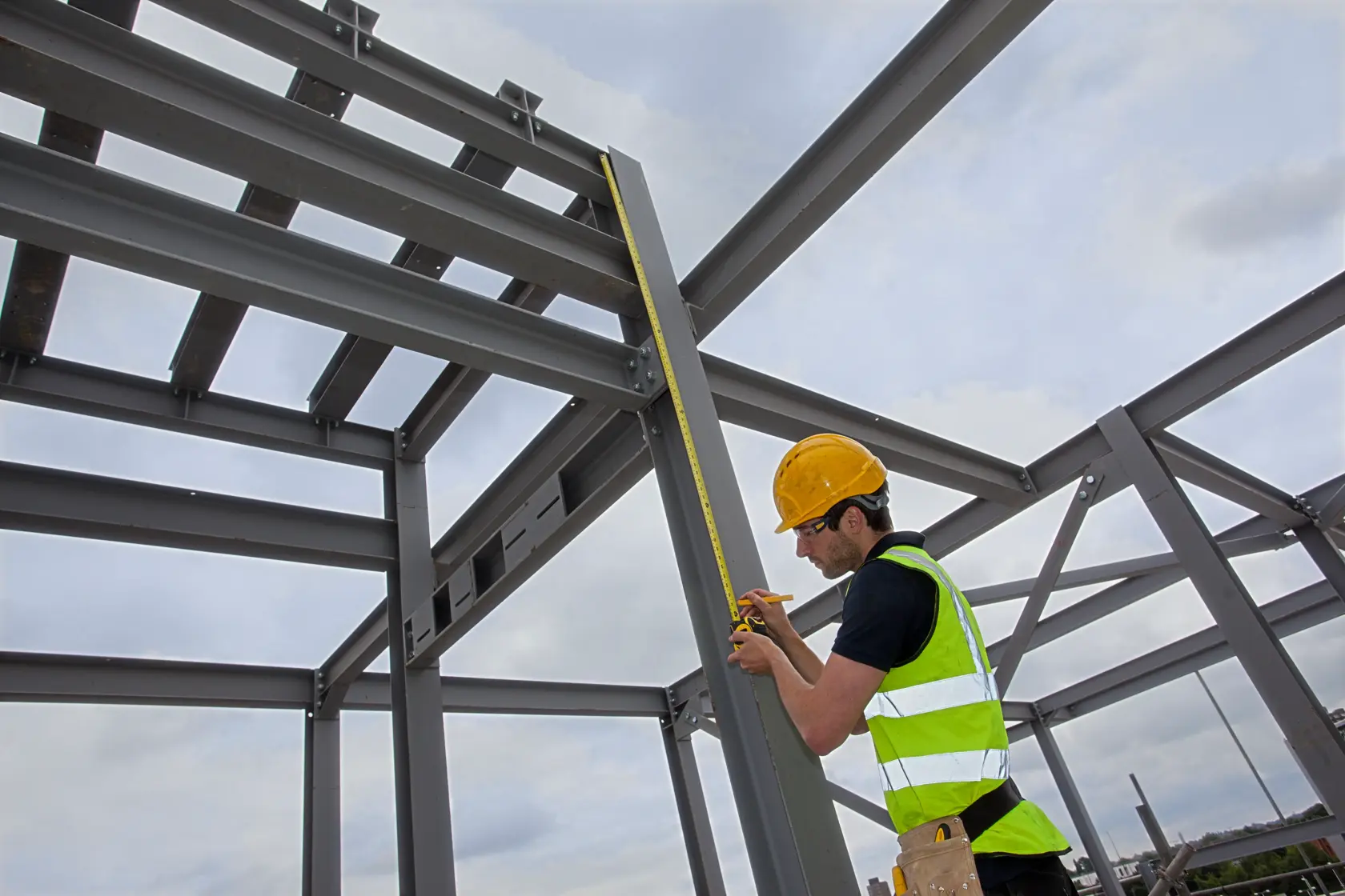 Photo of STANLEY XTHT0-33671 tape measure used by worker measuring steel frame structure outdoors.